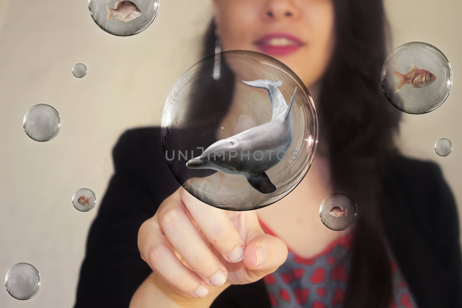 Portrait of a beautiful young woman pointing her finger to dolphin in bubble