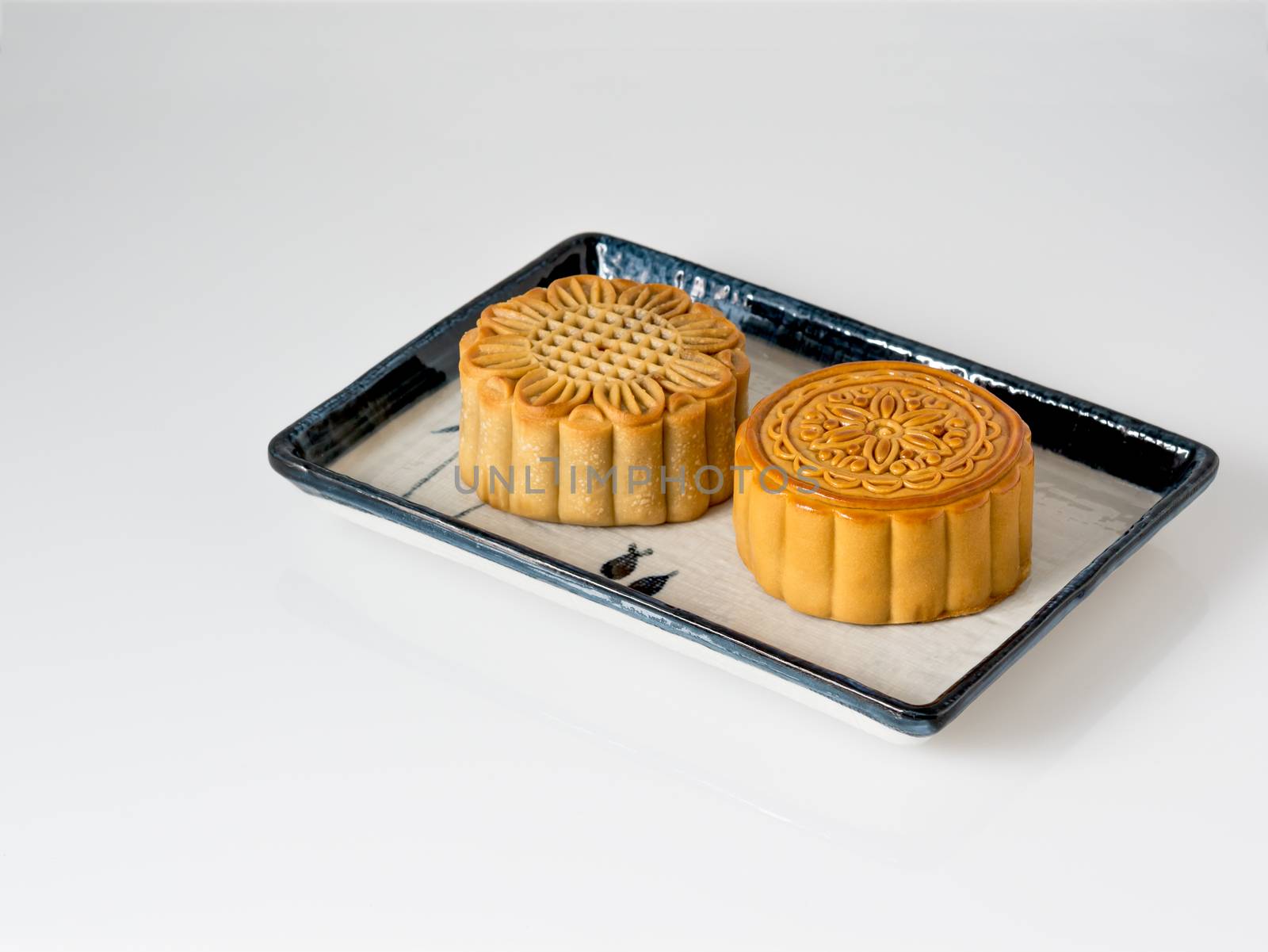 Mid autumn festival dessert, flower pattern moon cakes in white plate on white background with soft shadow