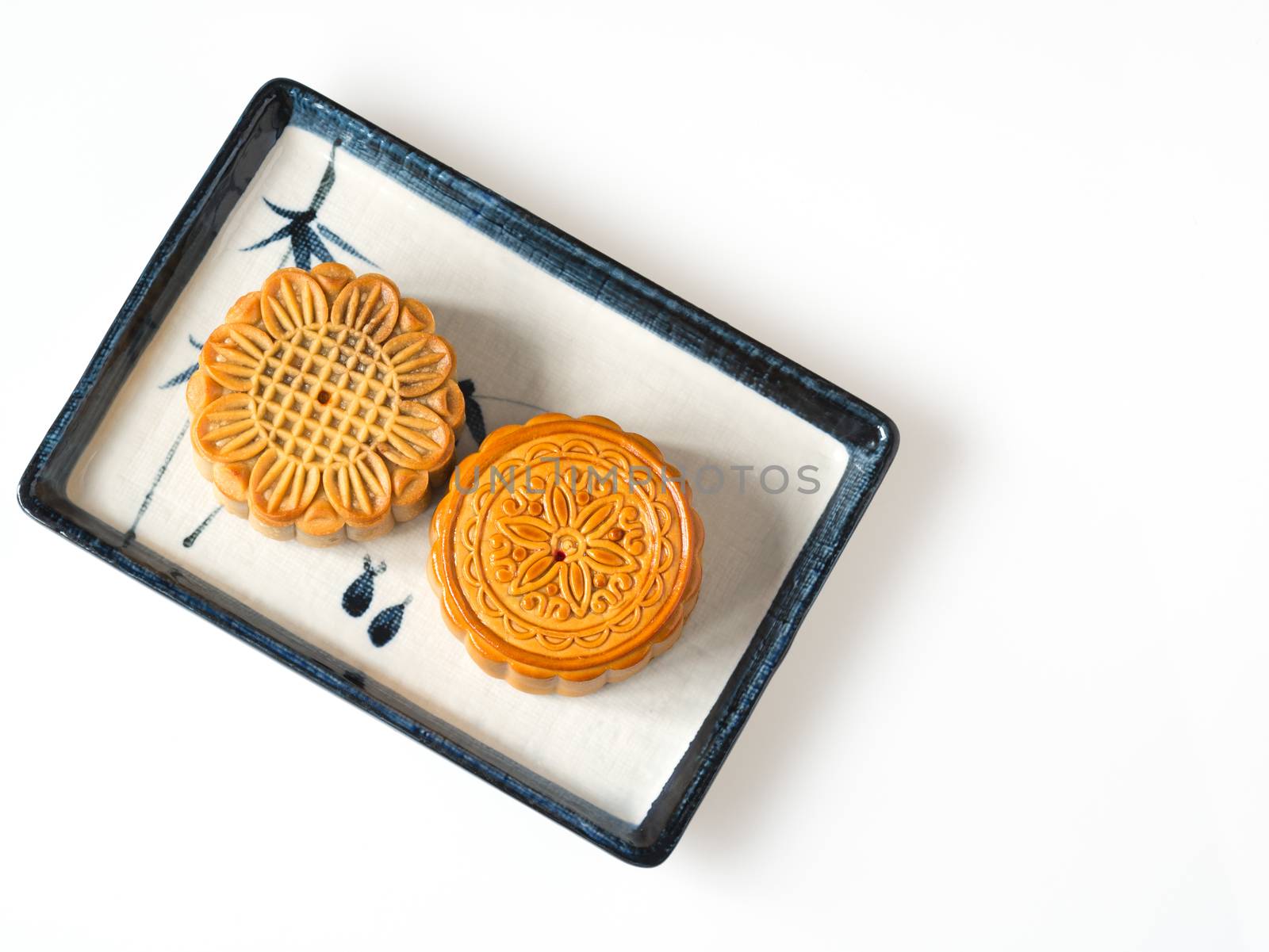 Mid autumn festival dessert, flower pattern moon cakes in white plate on white background with soft shadow