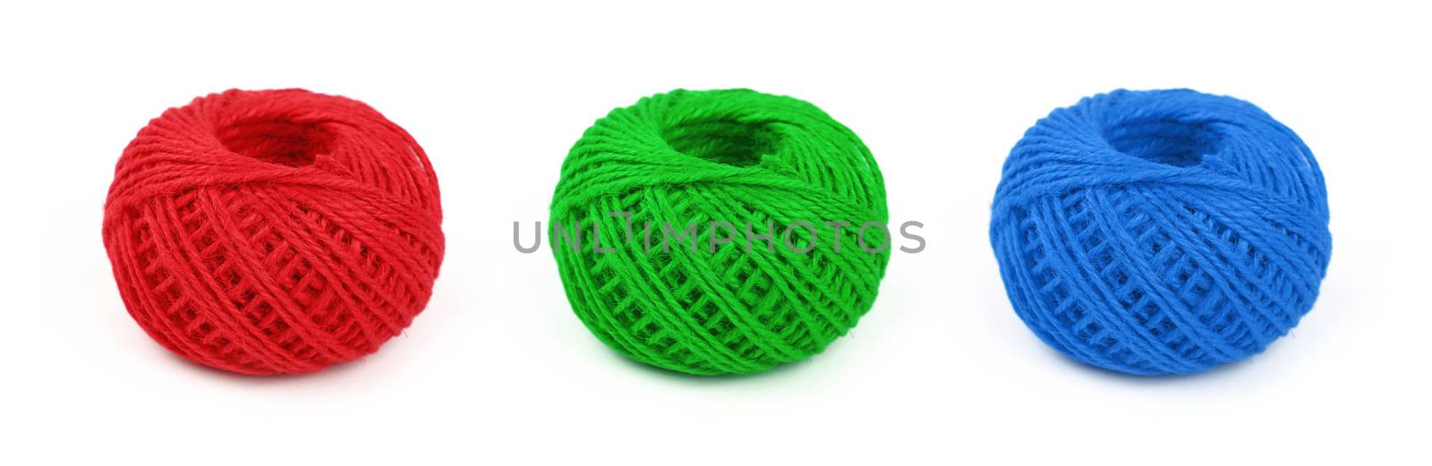 Three colorful multicolor small round coil bobbins of natural red, green and blue twine hessian burlap jute rope isolated on white background, close up, high angle view