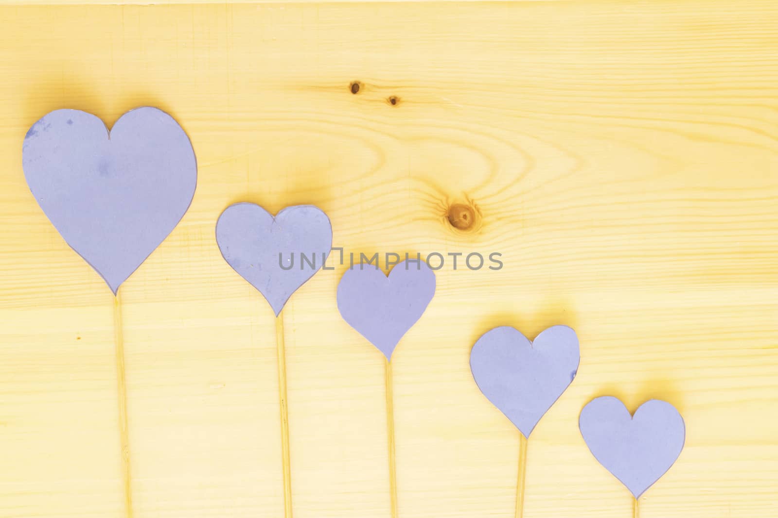 four blue heart paper with wooden stick on wood table by sigoisette