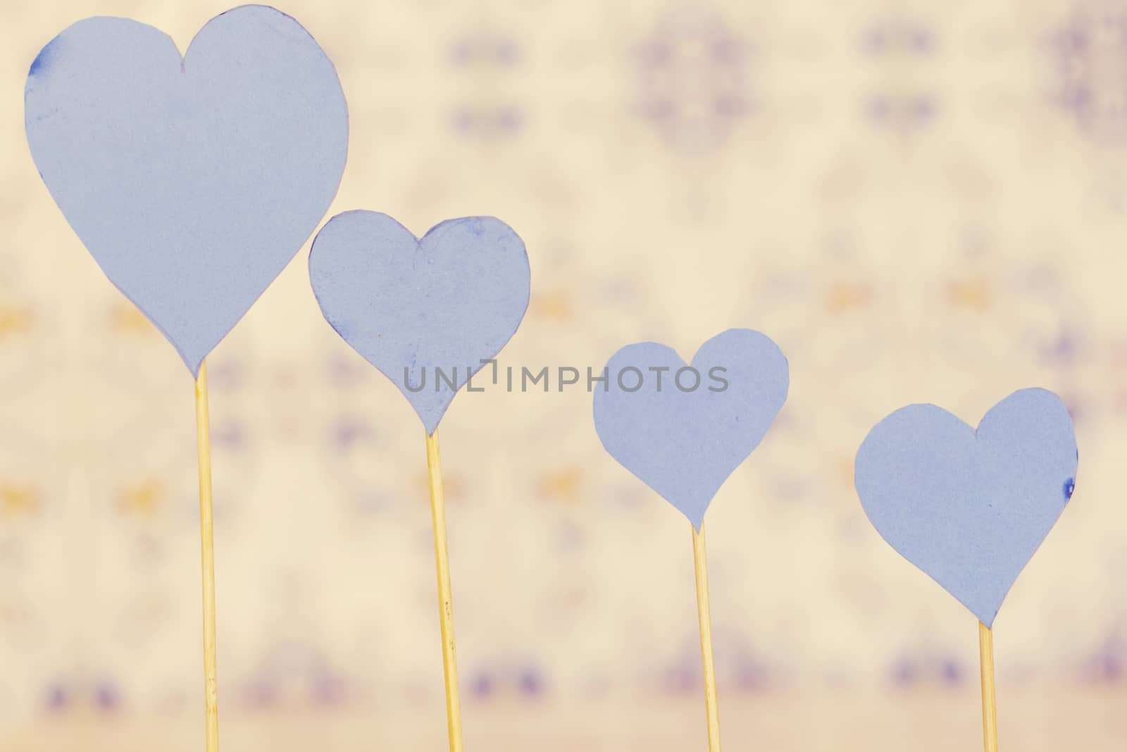 four blue heart paper with wooden stick on blue background by sigoisette
