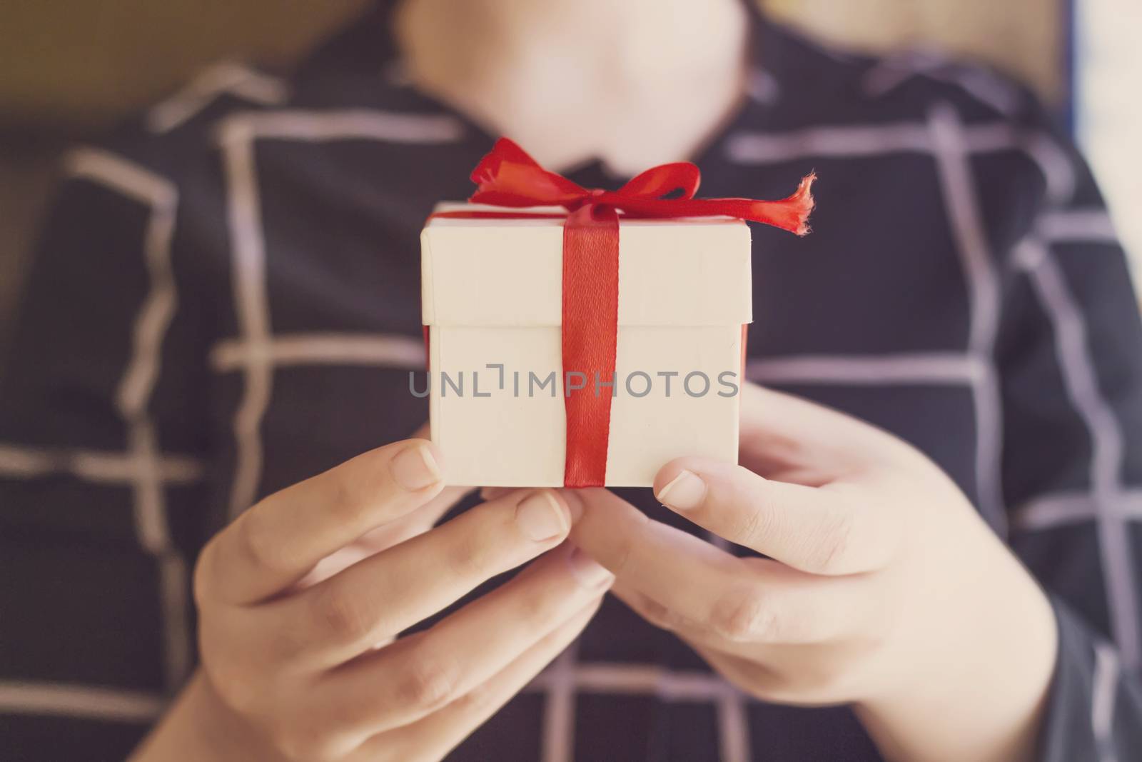 Young beautiful woman holding Christmas present in his hands in front of a beautifully decorated Christmas by sigoisette