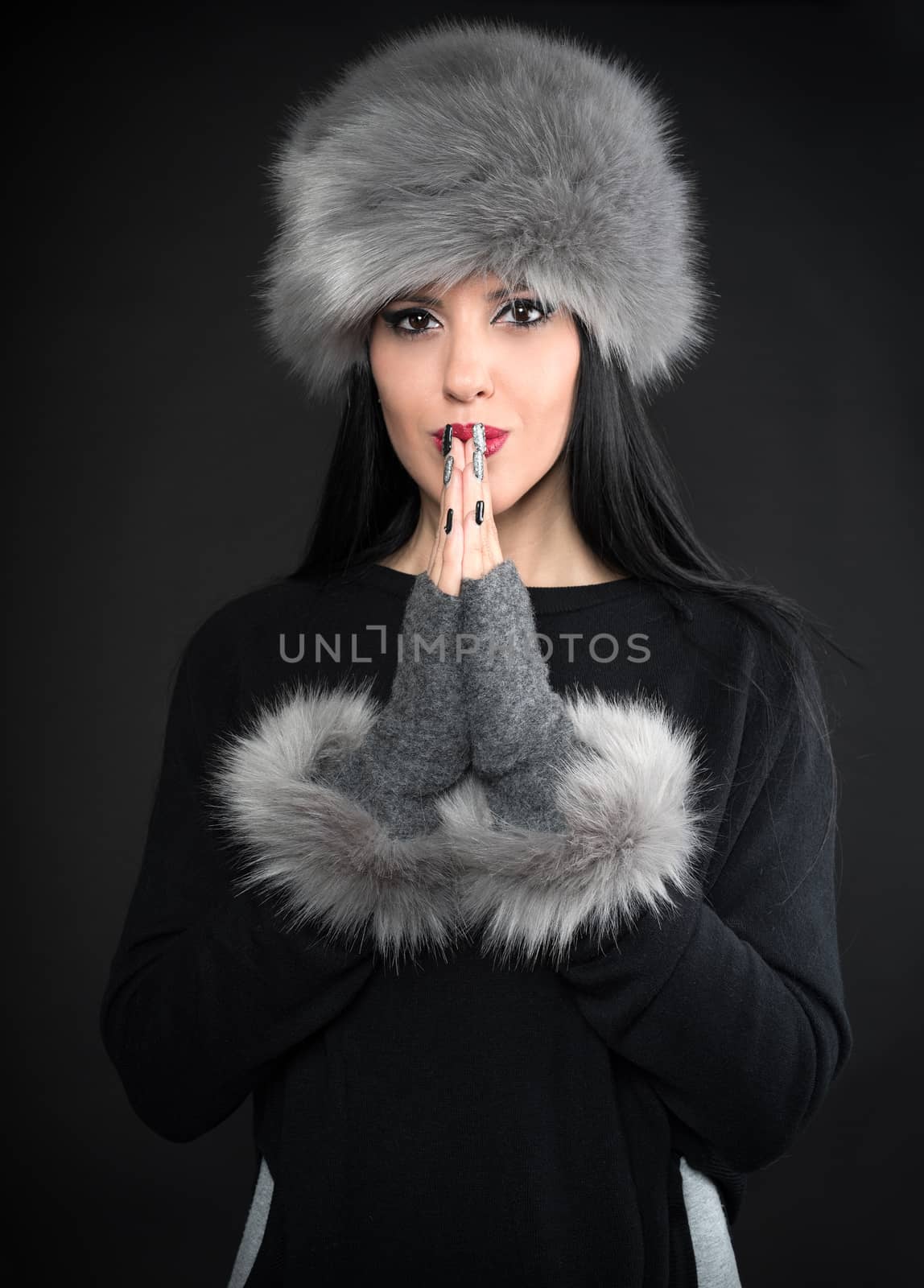 Winter portrait of a young smiling woman in a gray hat and gloves


