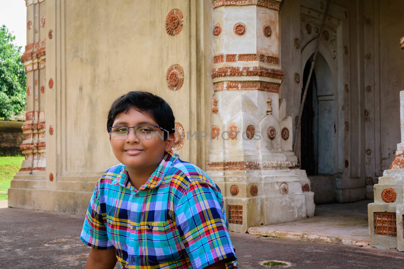 Young Bengali boy in front of Ancient Hindu terracotta temples of worship of Bengal with copy space