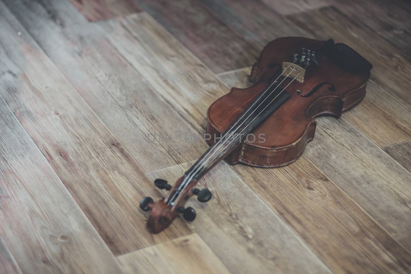 Old violin lying on a wooden surface by sermax55