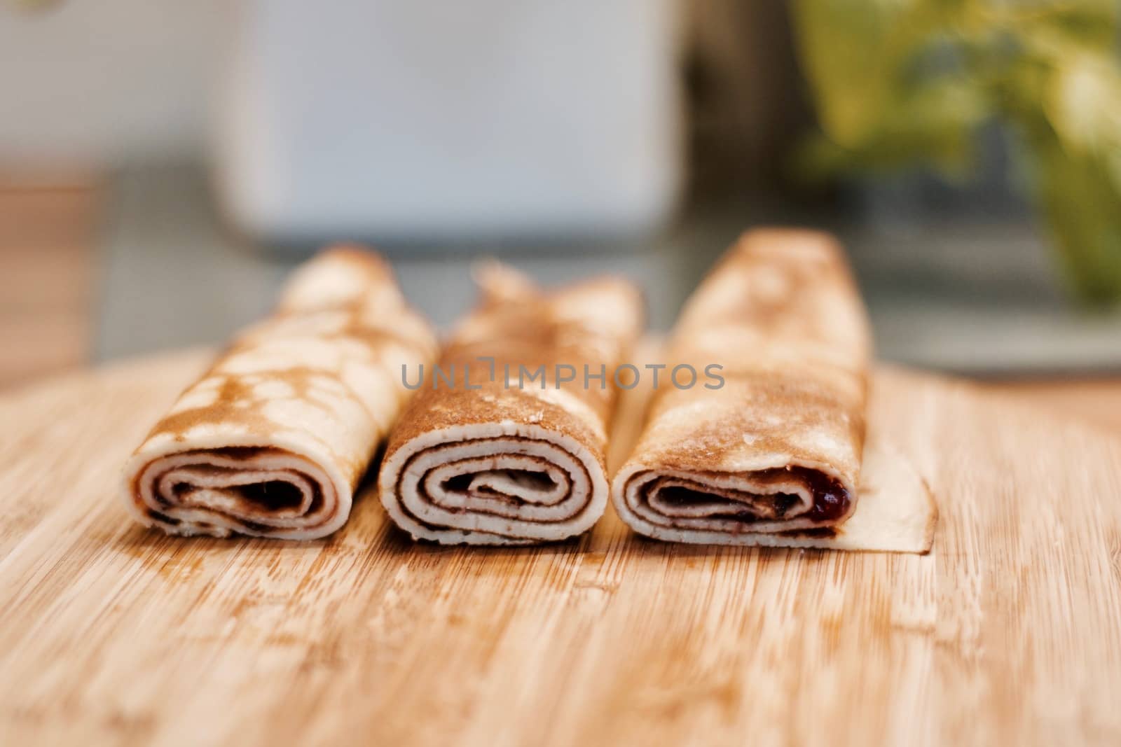Delicious and fresh pancakes with strawberry sauce on the wooden board in the kitchen.