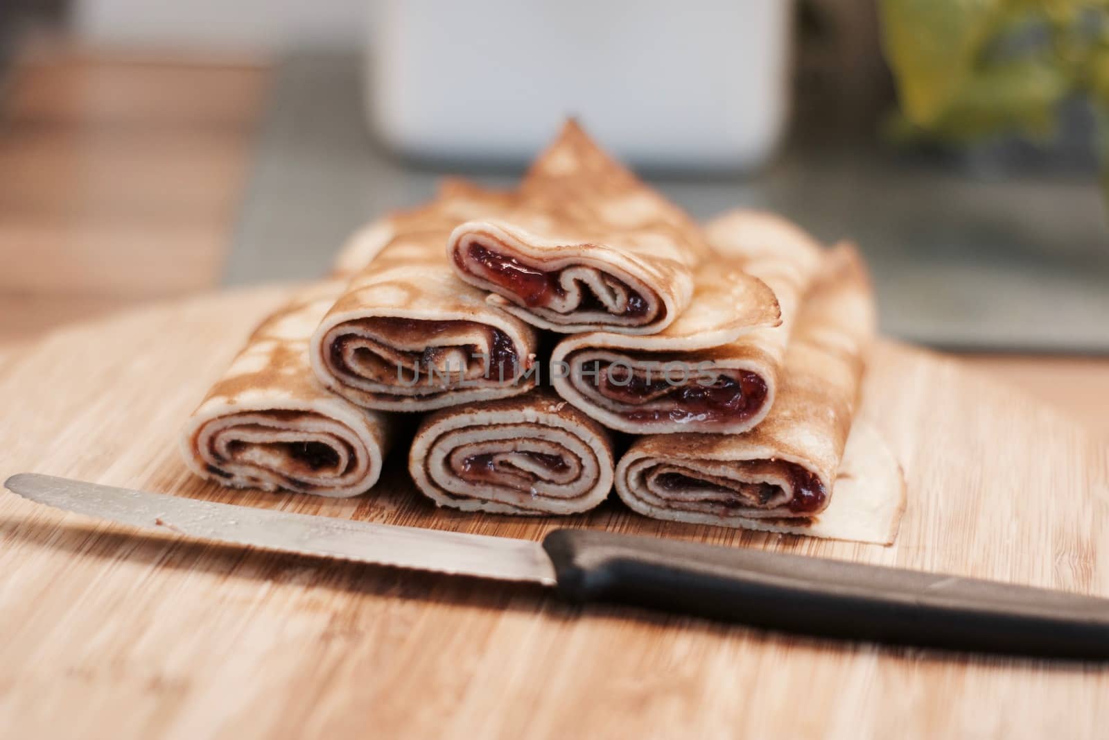 Delicious and fresh pancakes with strawberry sauce on the wooden board in the kitchen.