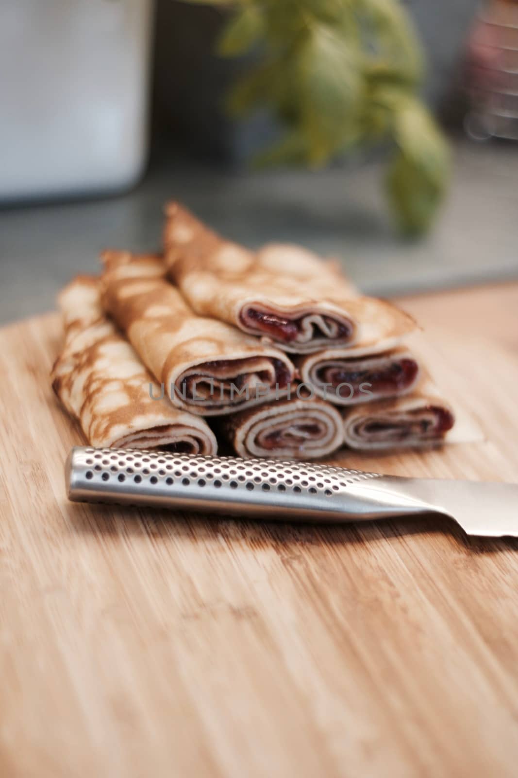 Delicious and fresh pancakes with strawberry sauce on the wooden board in the kitchen.