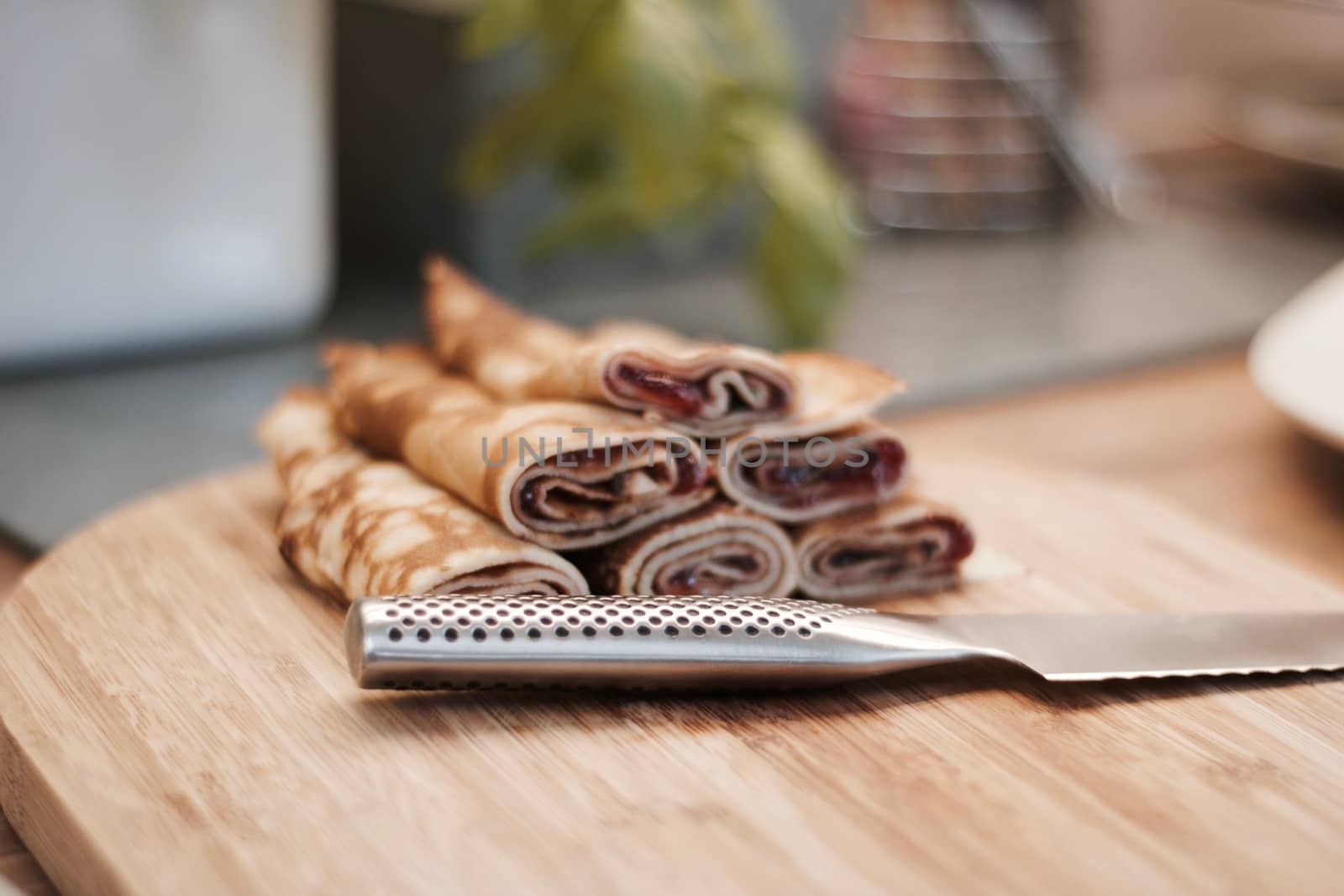 Delicious and fresh pancakes with strawberry sauce on the wooden board in the kitchen.