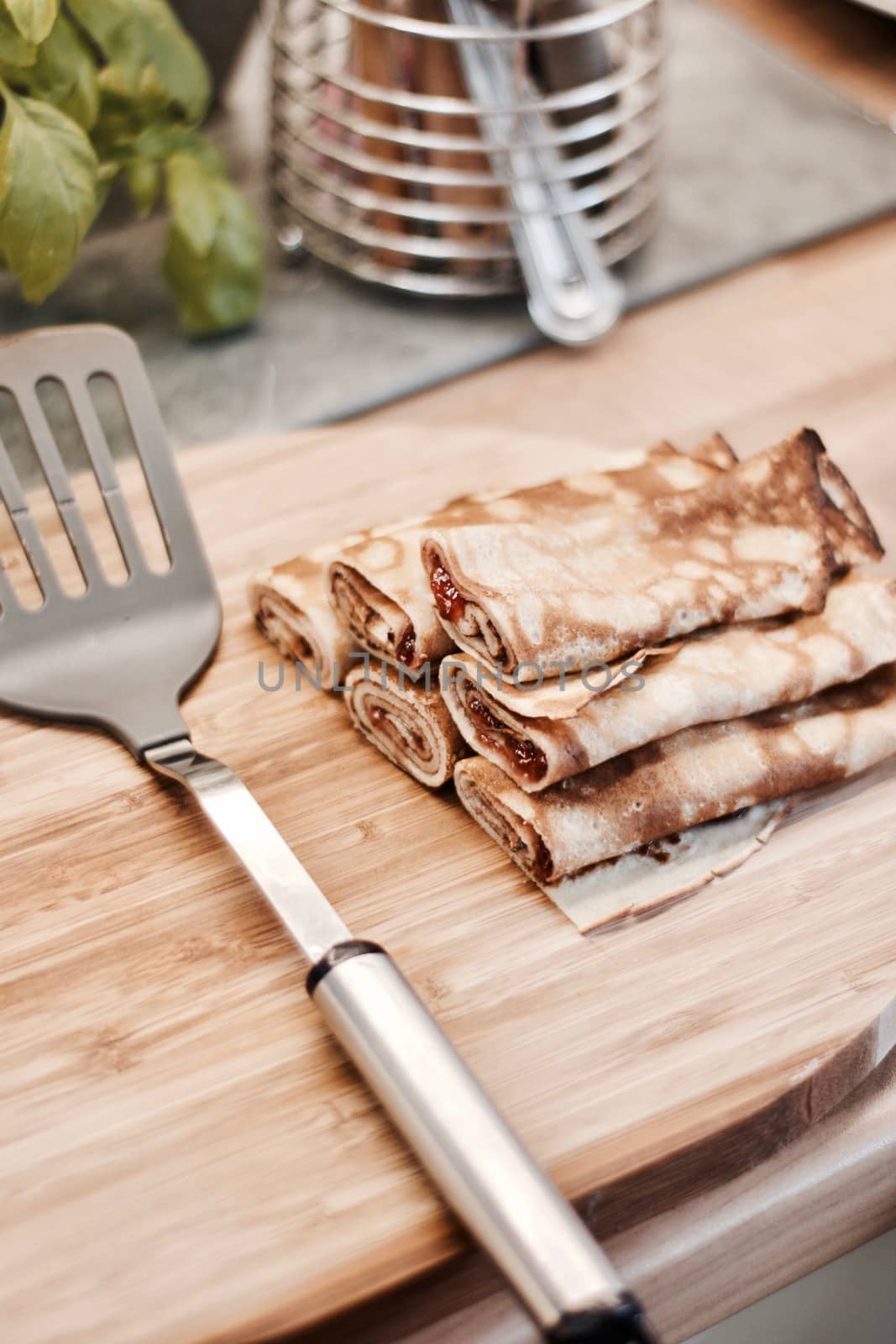 Delicious and fresh pancakes with strawberry sauce on the wooden board in the kitchen.