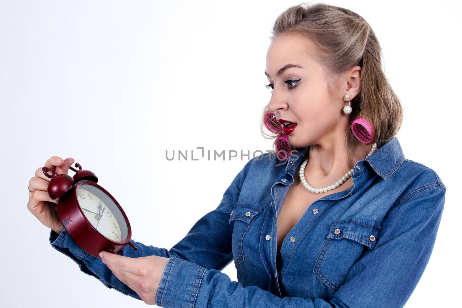 Frightened young woman in curlers with alarm clock