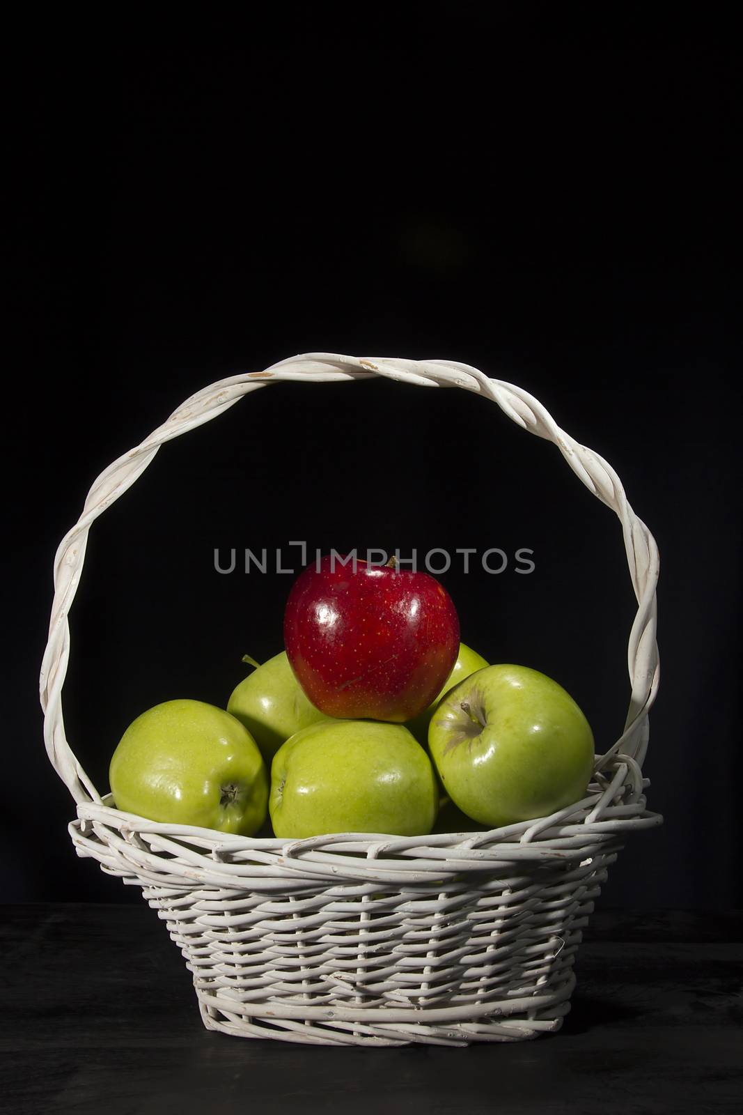 Ripe apples in a wicker basket on a black background