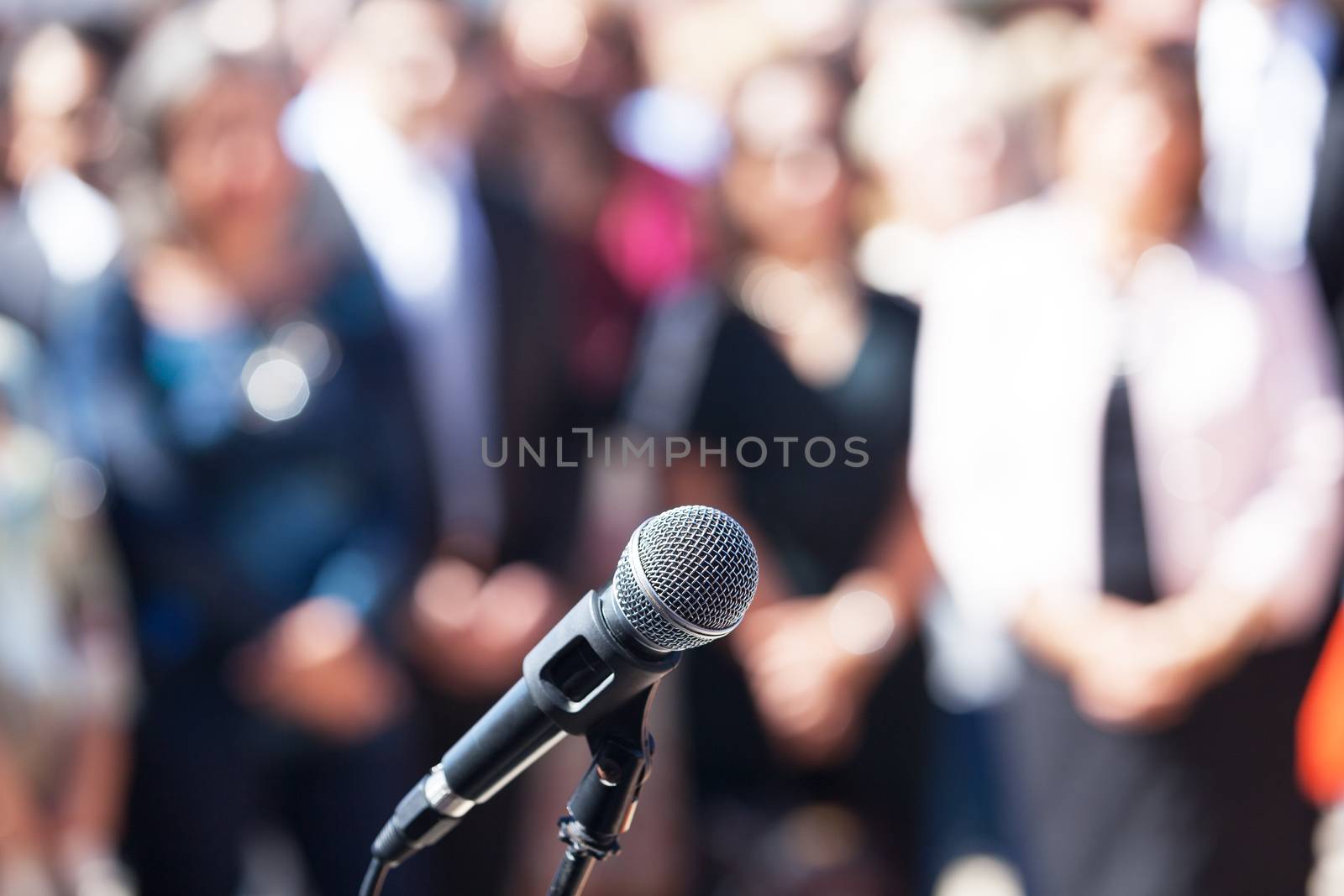 Microphone in focus against blurred audience by wellphoto