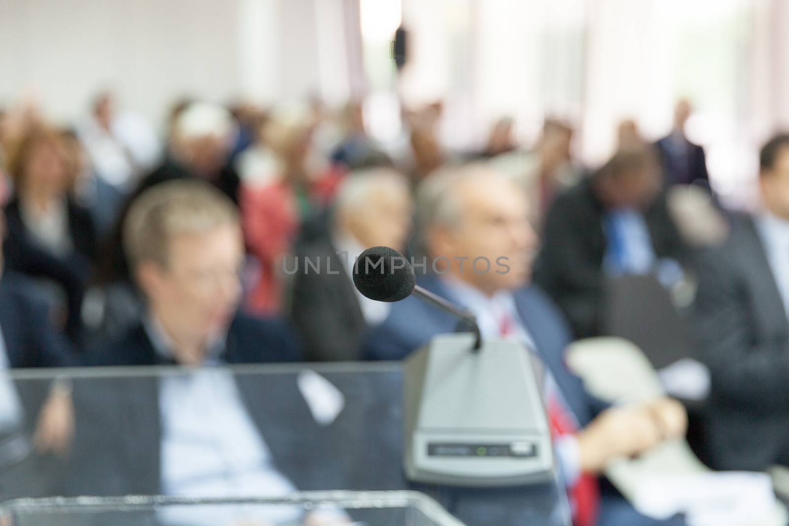 Microphone in focus against blurred audience. Participants at the professional or business conference.