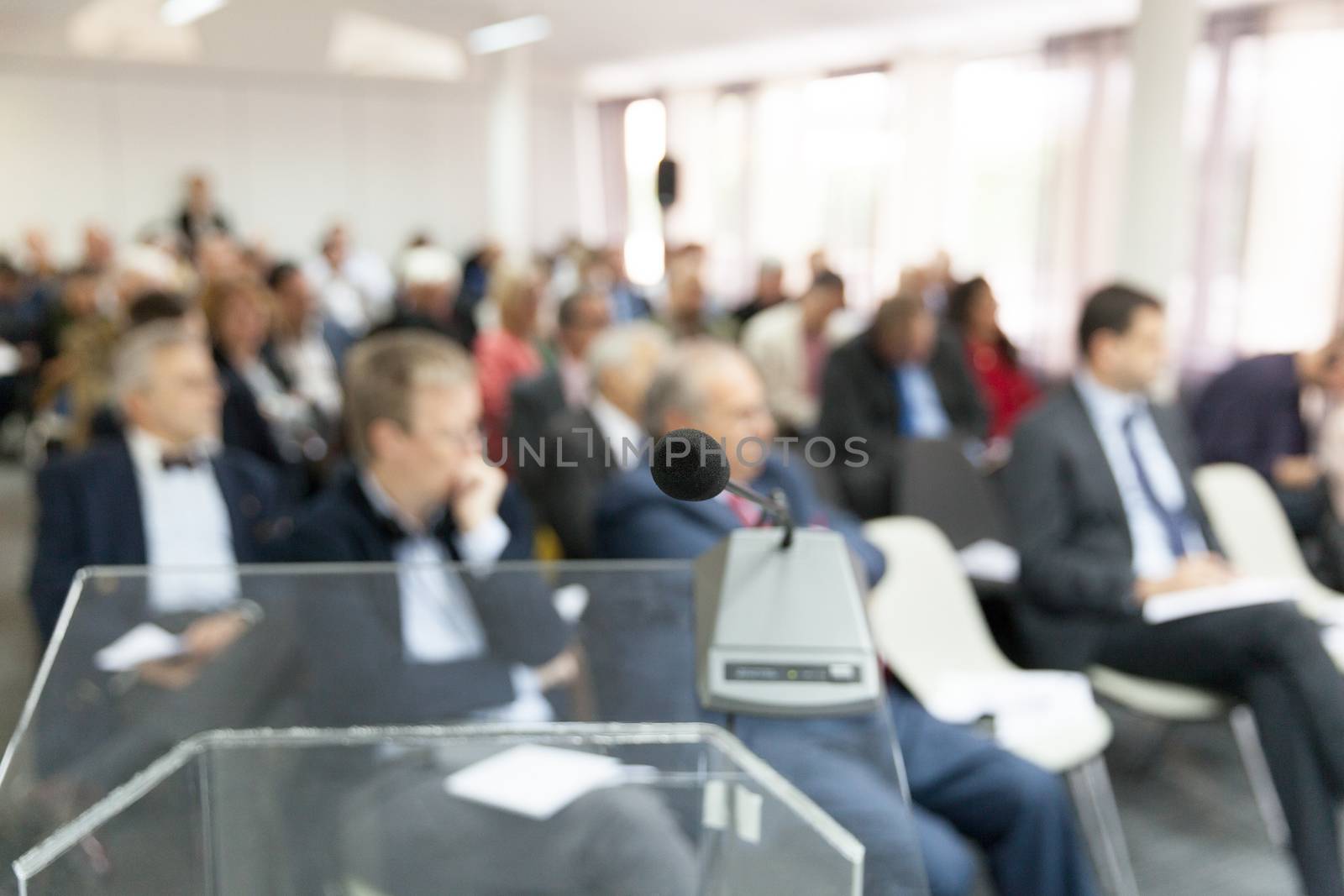 Microphone in focus against blurred audience. Participants at the business or professional conference.