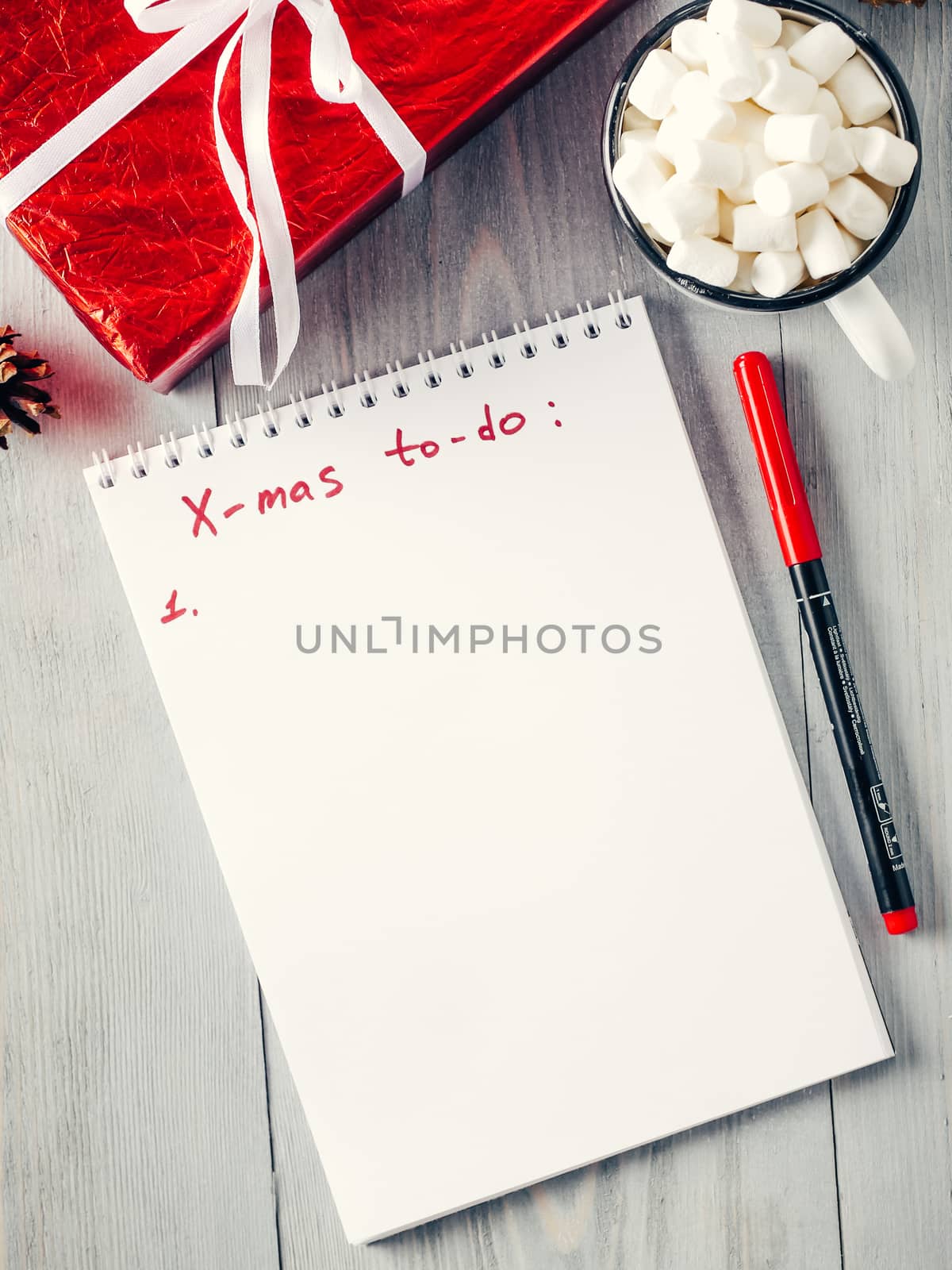 Christmas to-do list. Xmas gifts shopping planning. Make shopping or to-do list for Christmas. Notebook, mug hot chocolate with marshmallows and New Year's gift on gray wooden background. Top view