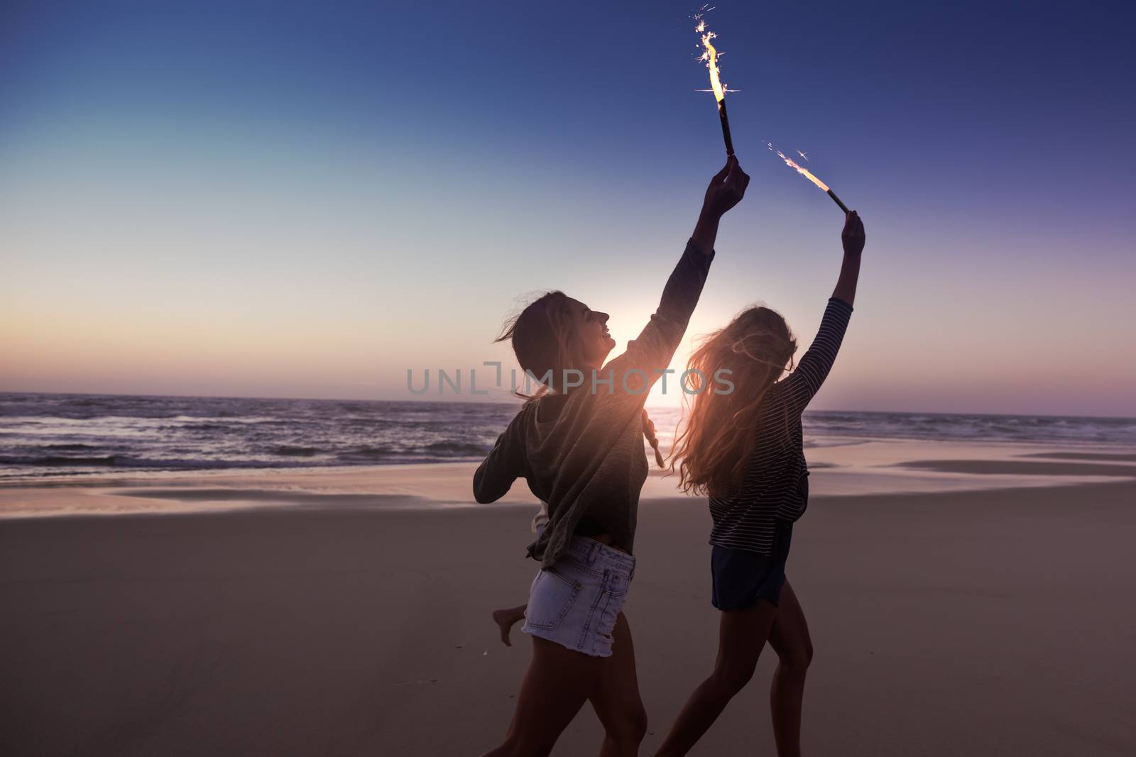 Teenage friends running on a beach with fireworks