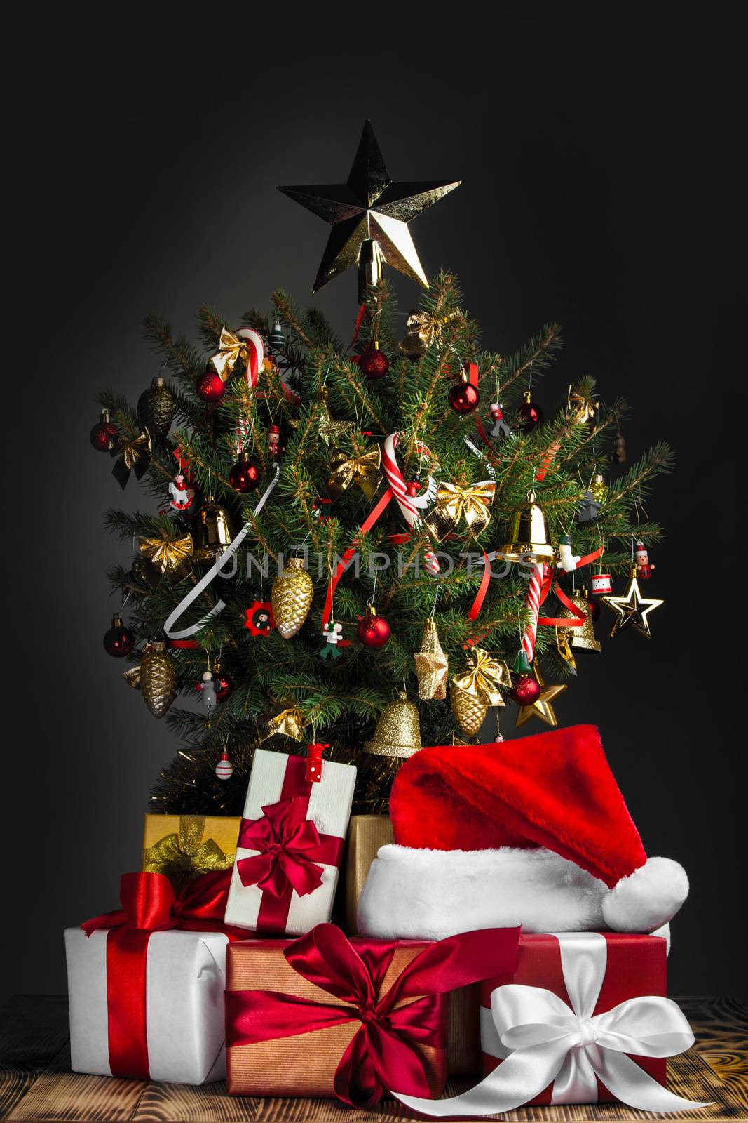 Decorated Christmas tree with glowing lights and gift boxes on dark background