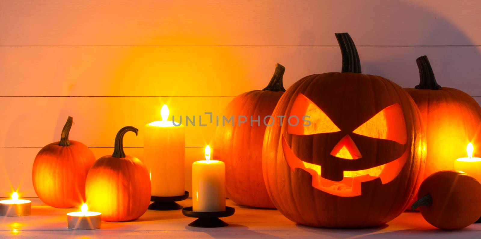Halloween pumpkin head jack lantern and candles on wooden background