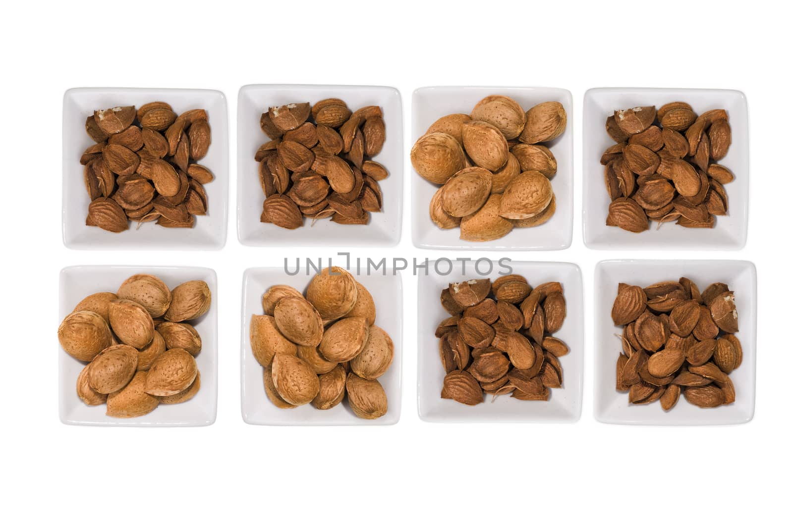 Composition with almonds white pots over white background.