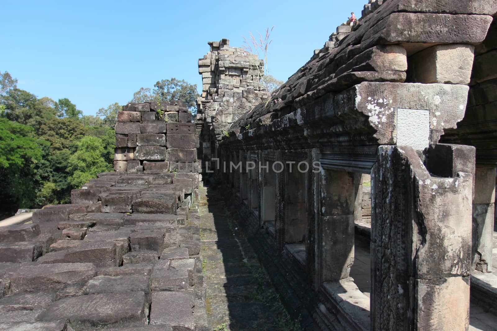 Brick and stone masonry of the ancient walls of the Cambodian temple, with reliefs and sculptures, pillars and columns on a natural background