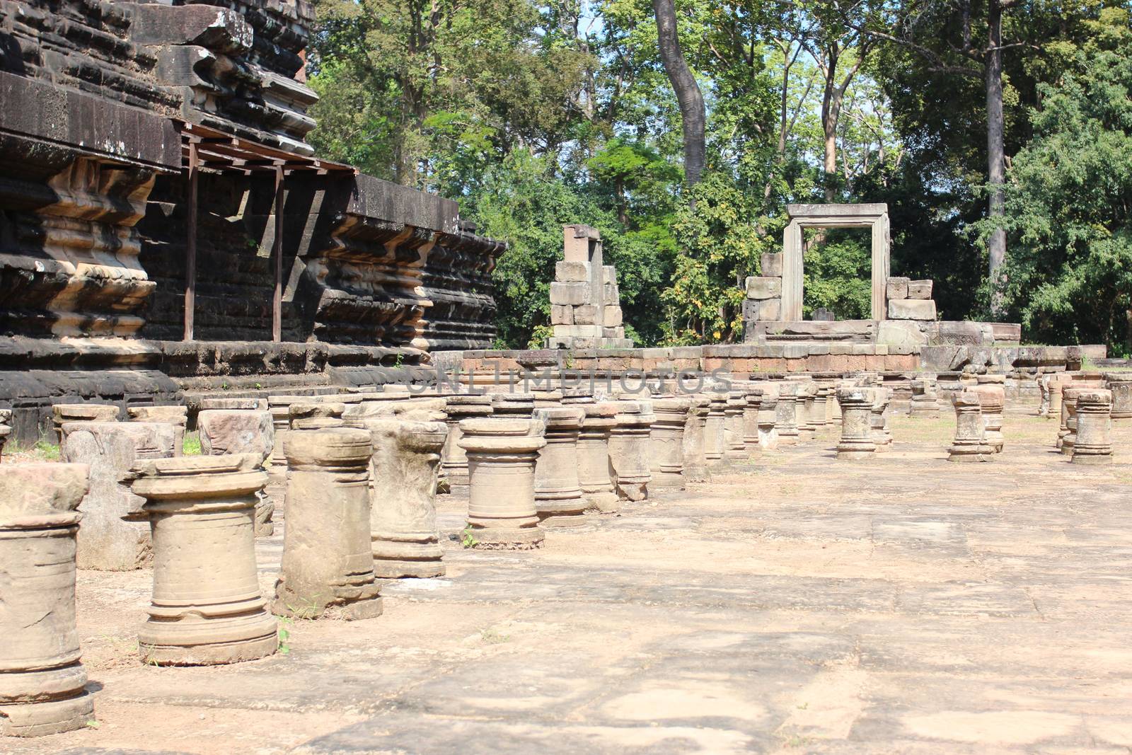 Brick and stone masonry of the ancient walls of the Cambodian temple, with reliefs and sculptures, pillars and columns on a natural background