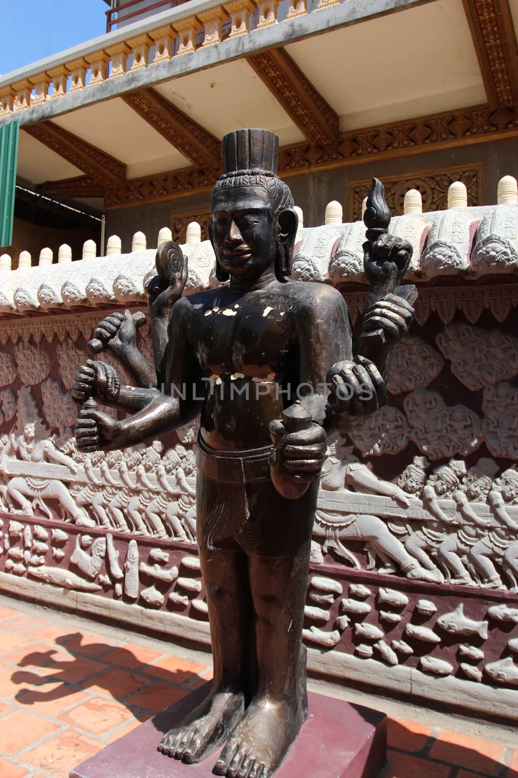 Buddhist sculpture, illuminated by the sun against a wall with relief