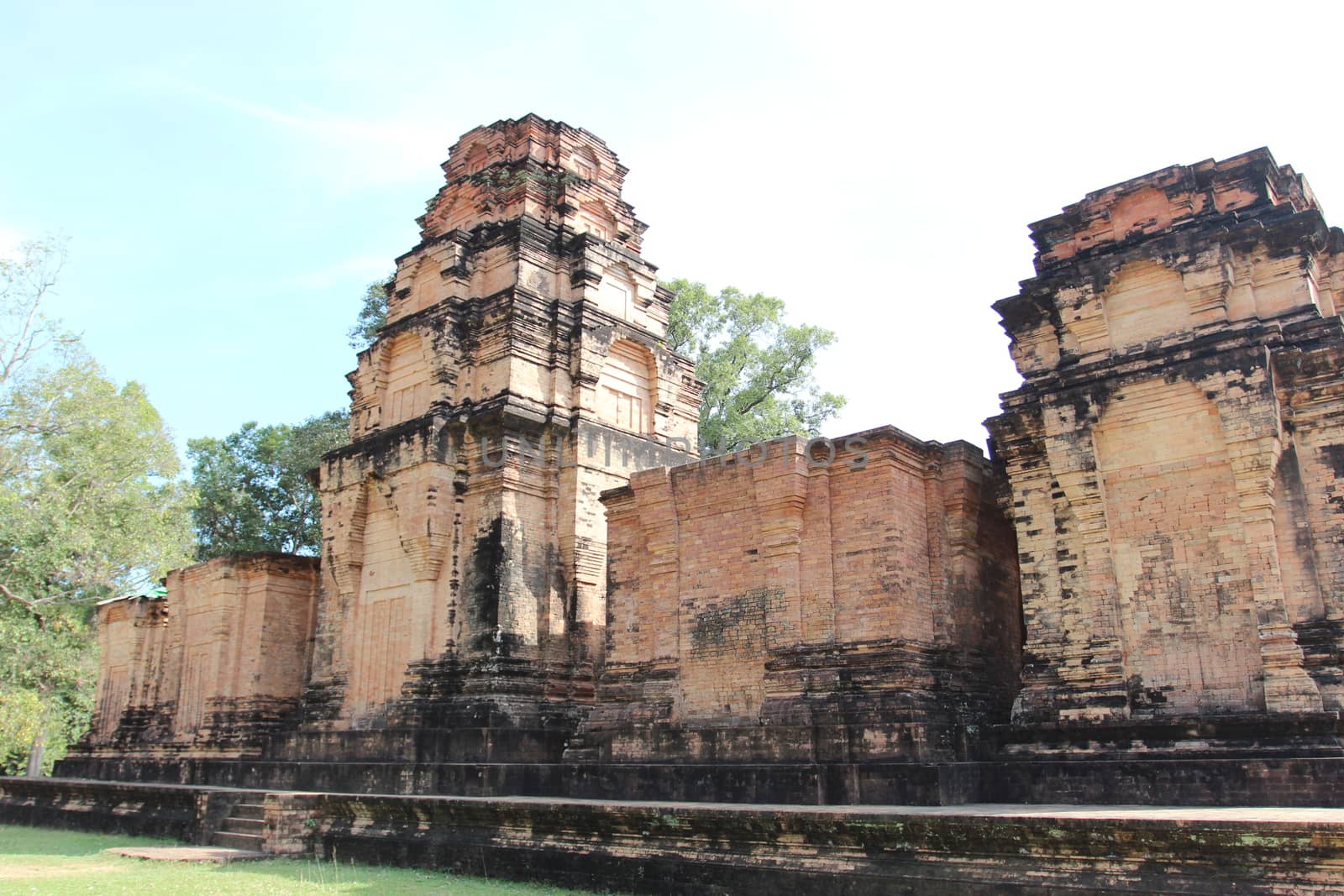 Brick and stone masonry of the ancient walls of the Cambodian temple, with reliefs and sculptures, pillars and columns on a natural background