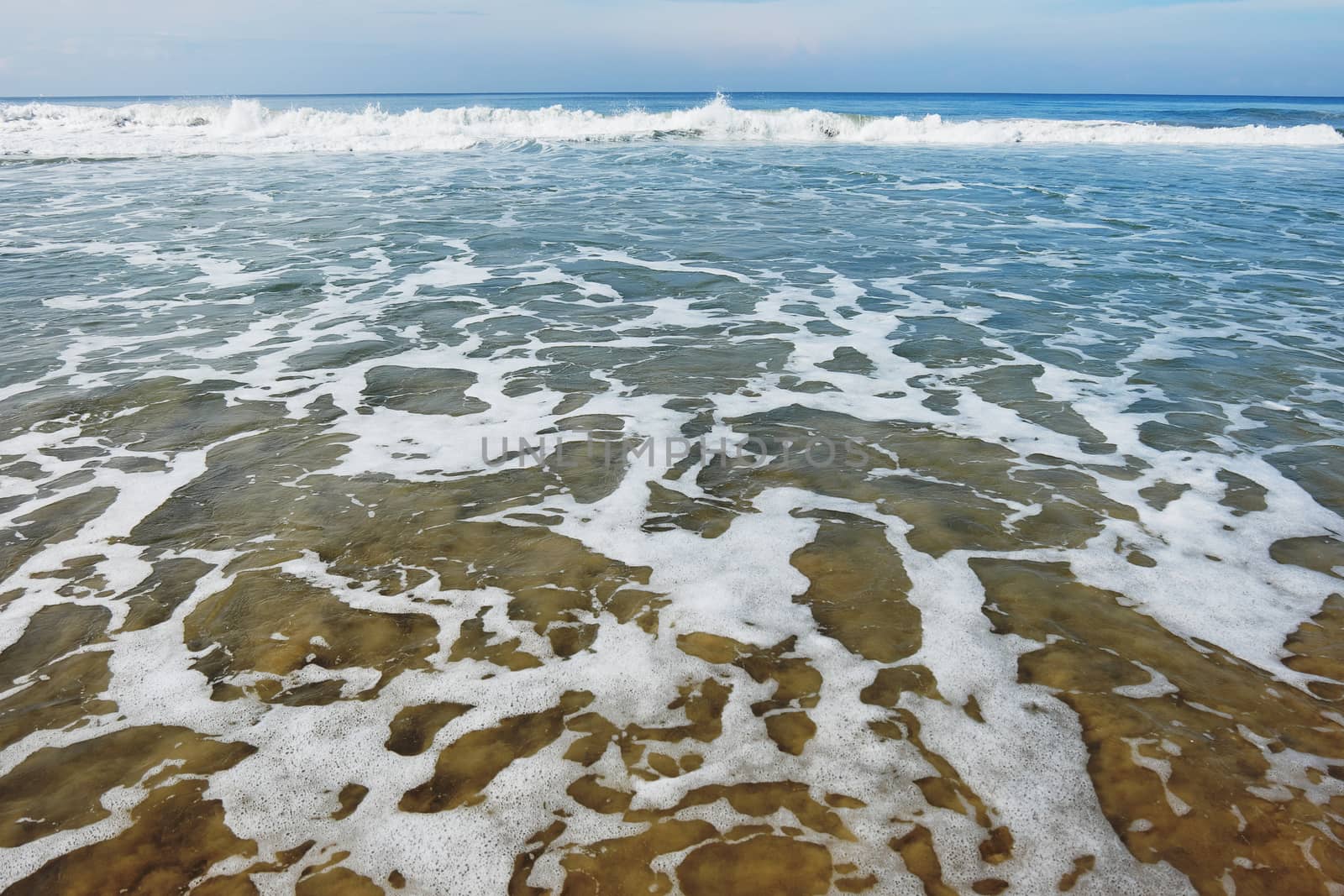 Indian Ocean in calm weather with small waves and many foam