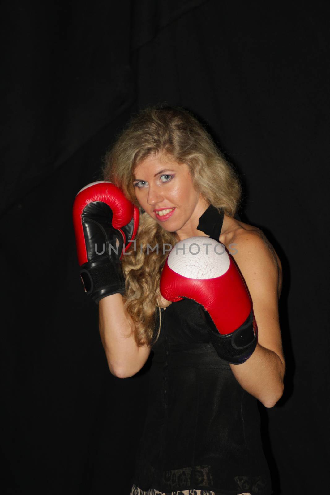 funny blonde girl in black casual dress in red boxing gloves