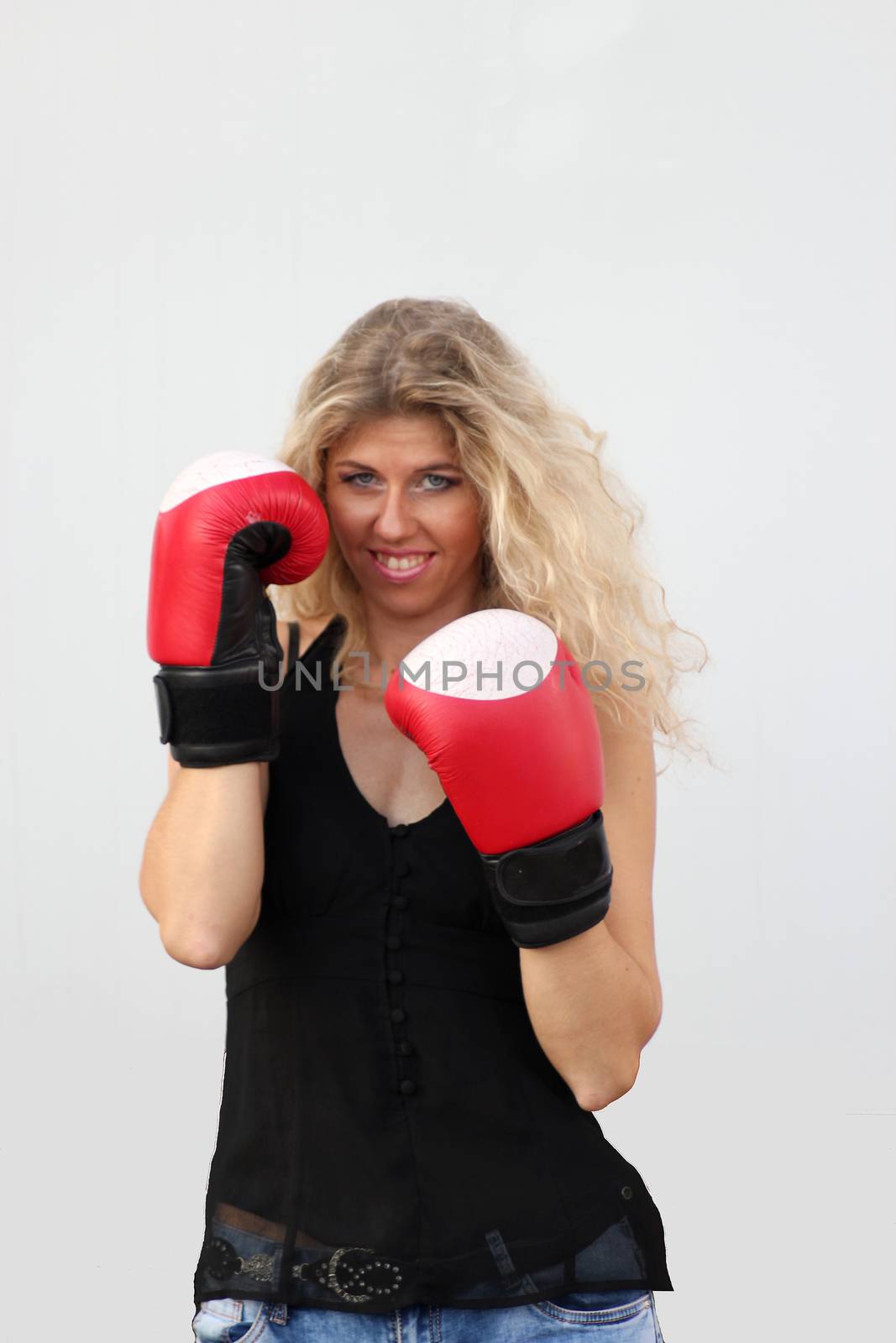 funny blonde girl in black casual dress in red boxing gloves