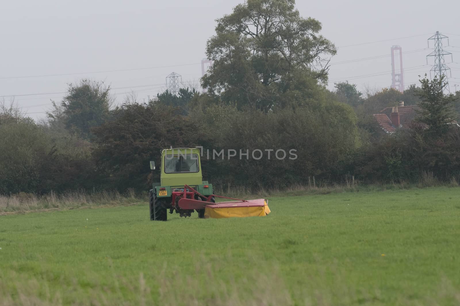 a farmer uses a tractor to cut a field of grass