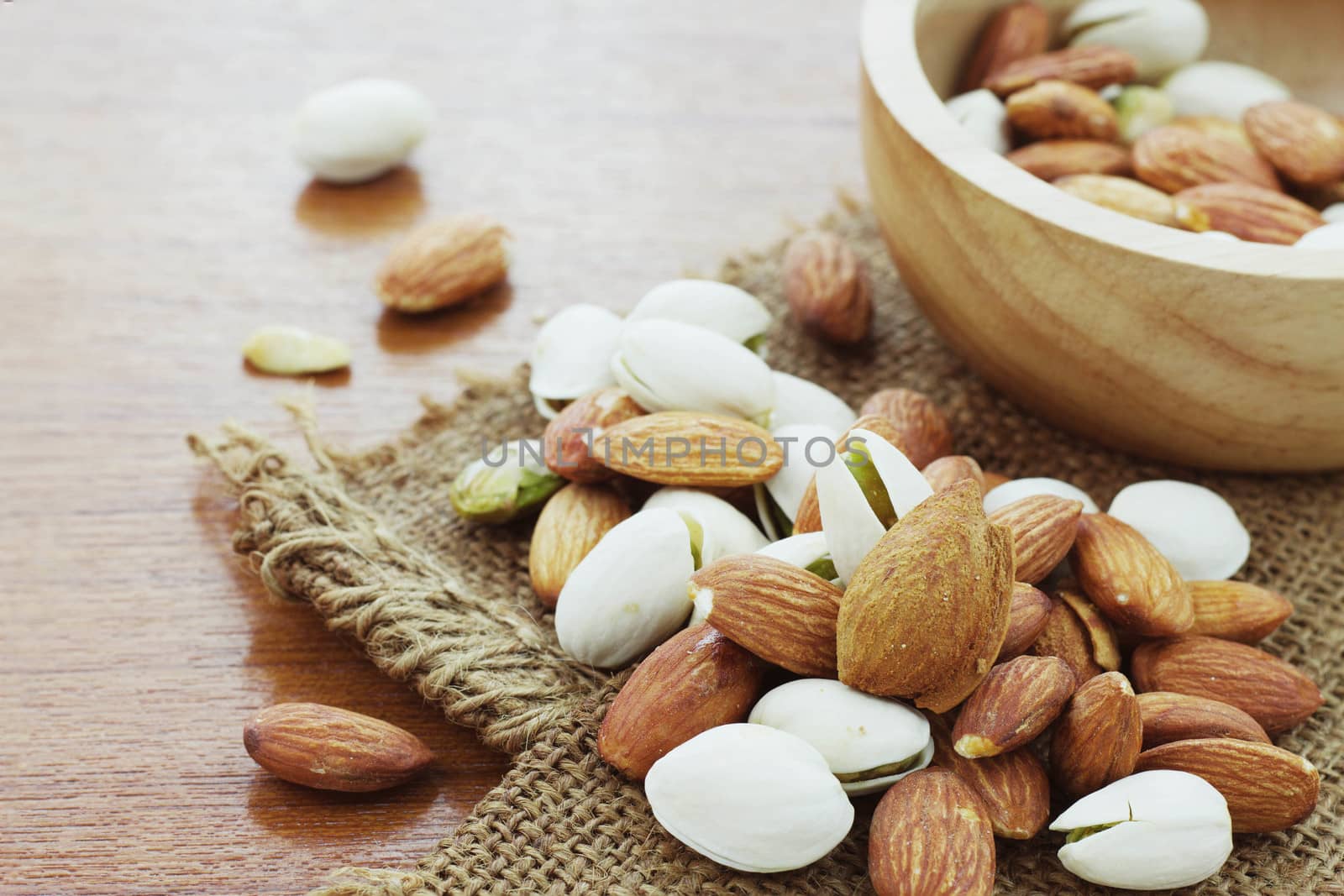 Almond mixed on sack with wooden background.