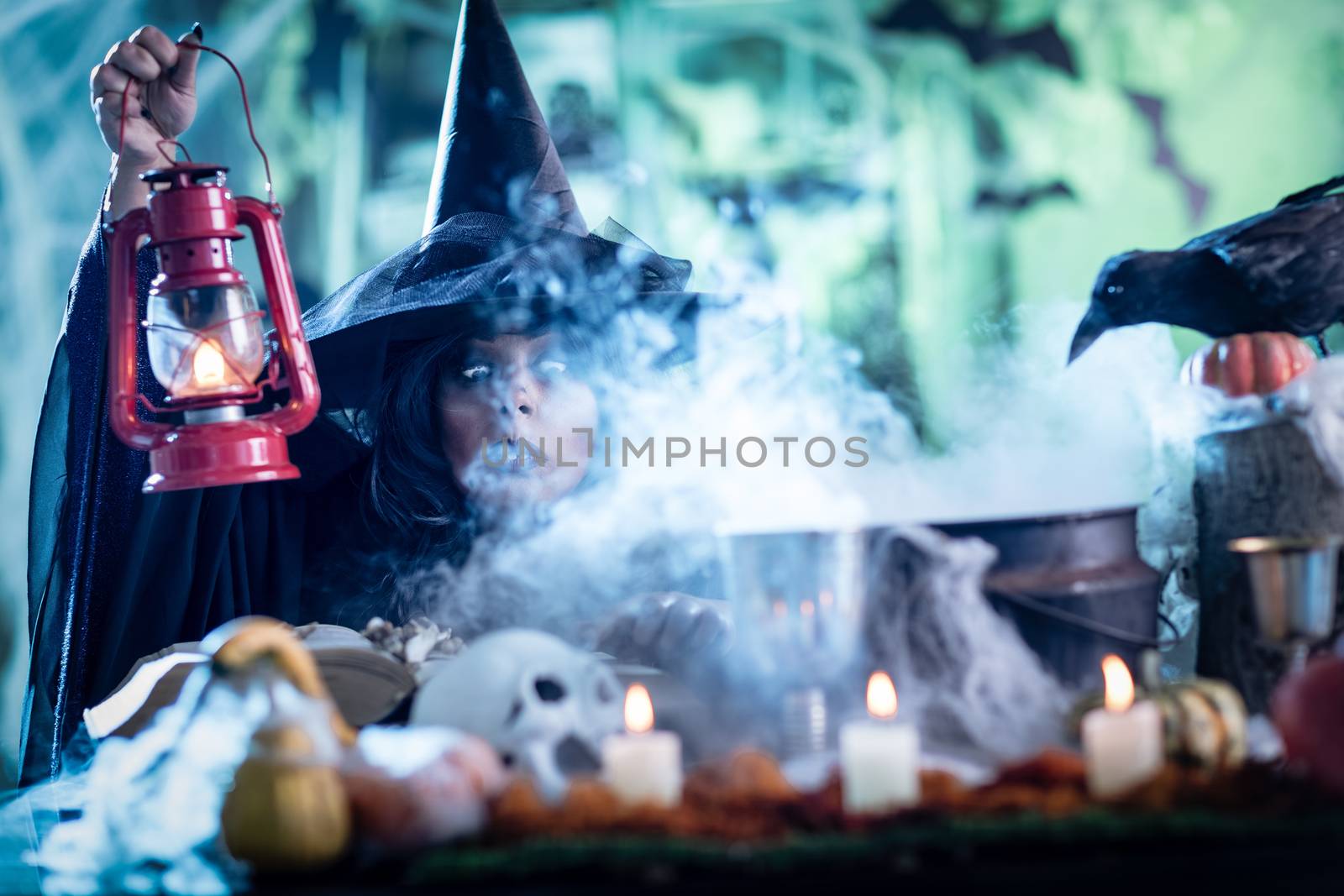 Witch with awfully face and lantern in her hand in creepy foggy surroundings sends evil. Halloween concept.