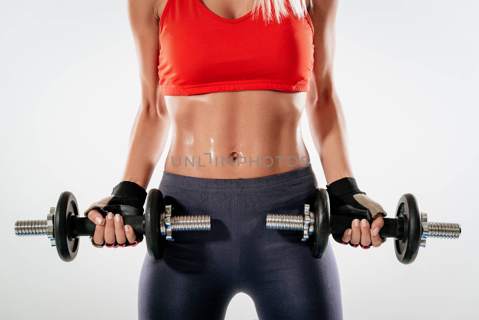 Close-up of a young muscular woman lifting dumbbells. Sport fitness concept.