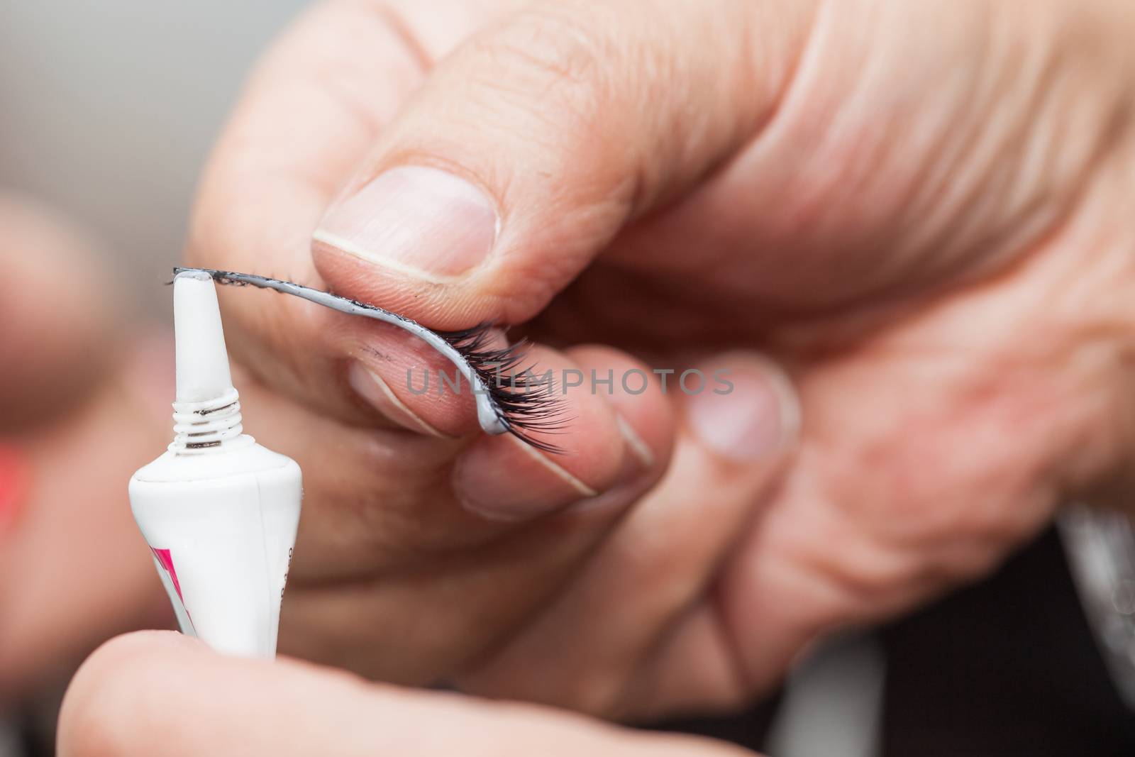 Close up of a make up artist hands applying cosmetic glue on fake eyelashes