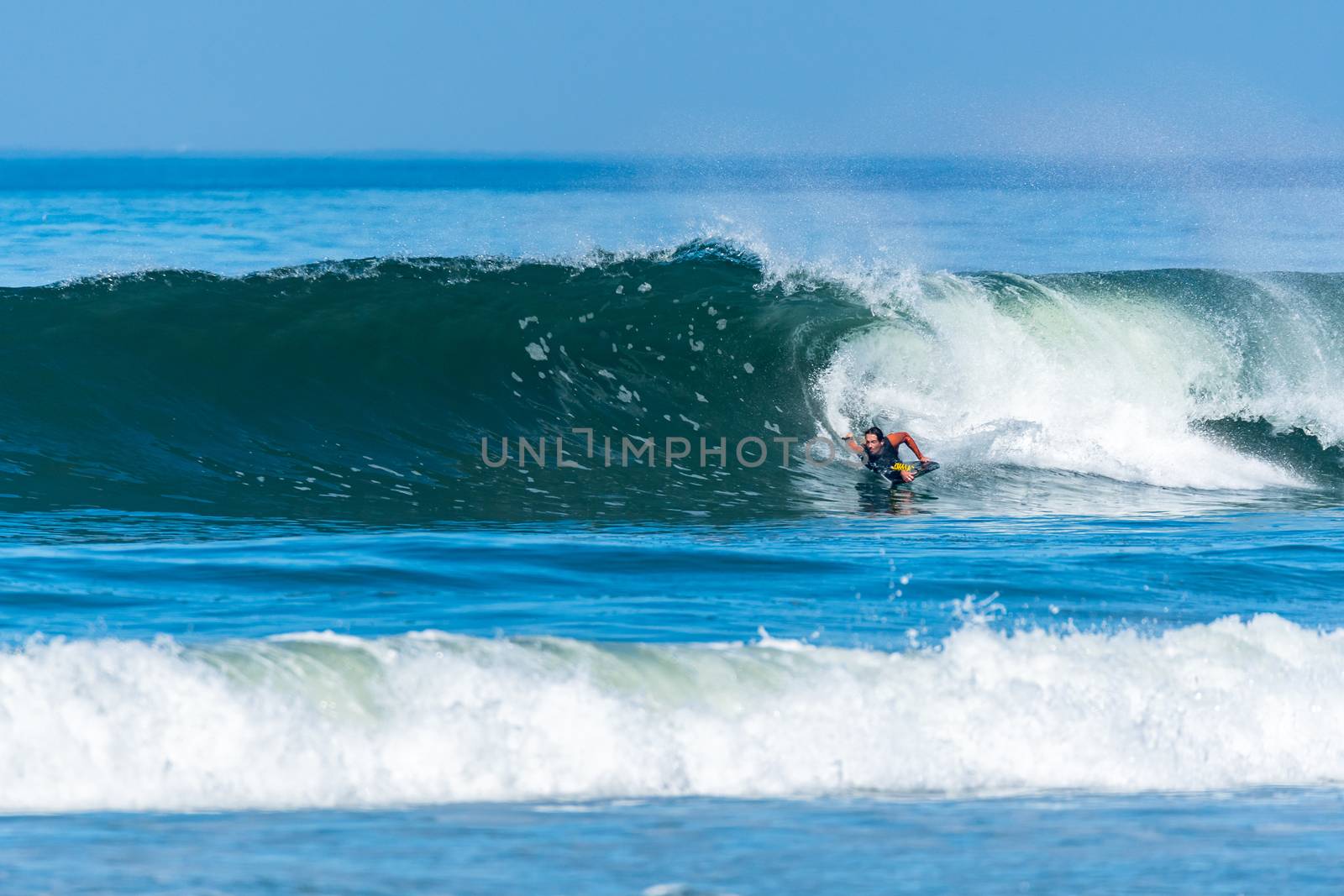 Bodyboarder in action on the ocean waves on a sunny day.