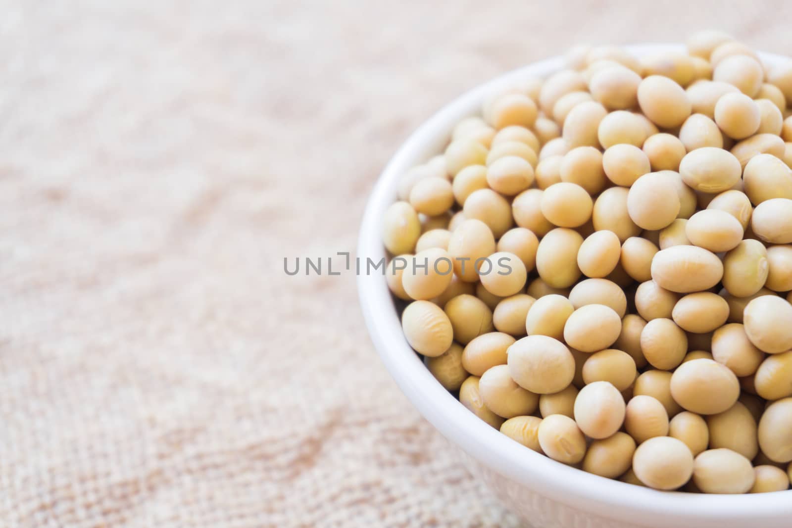 Closeup soy beans on white bowl with sackcloth background , healthy food concept
