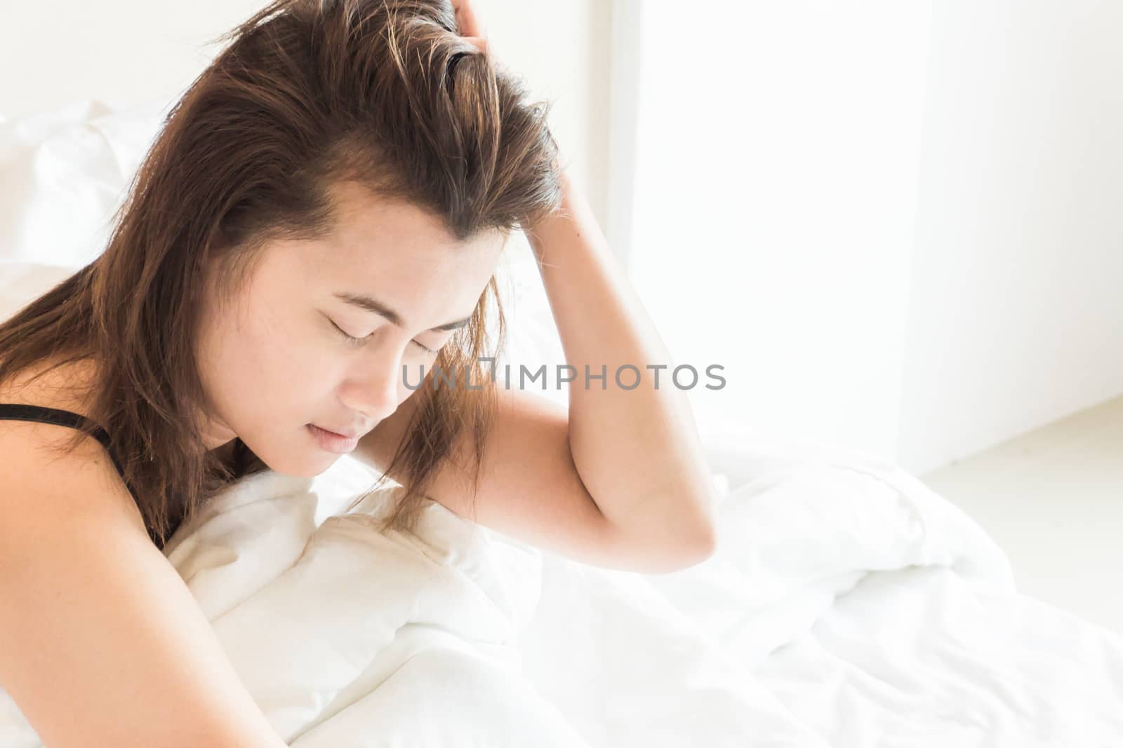 Closeup woman waking up with sore head on bed, health care and medical concept, selective focus