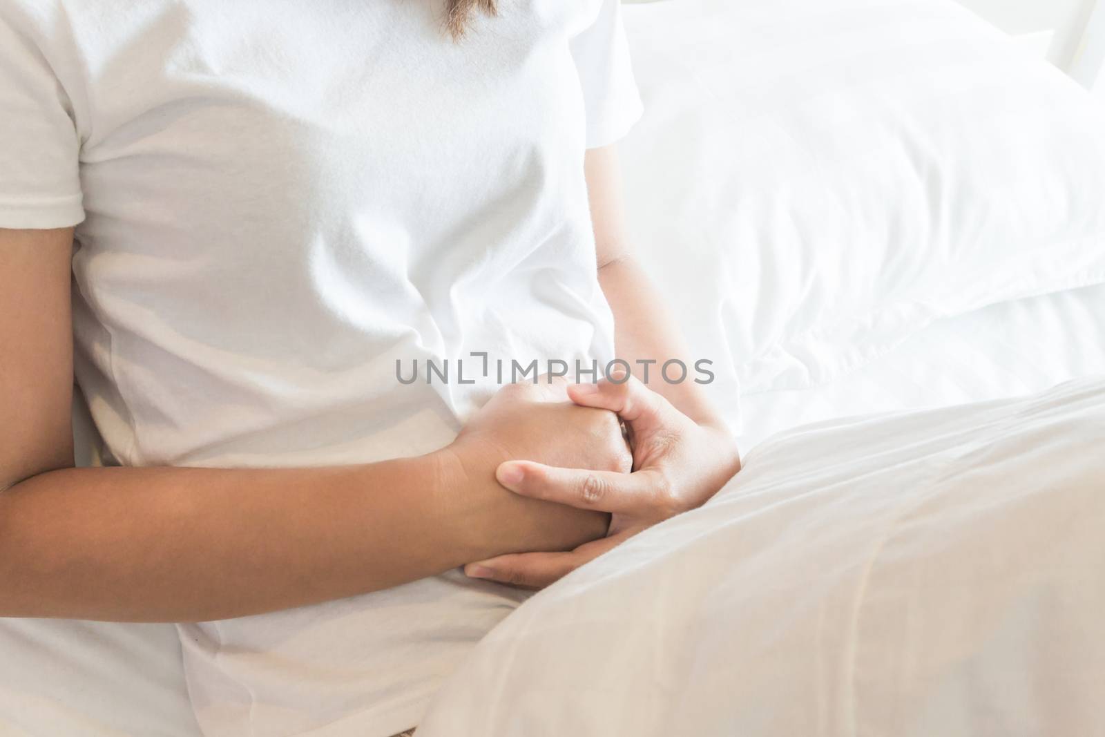 Closeup woman hand holding abdominal with stomach ache lying on bed, health care and medical concept