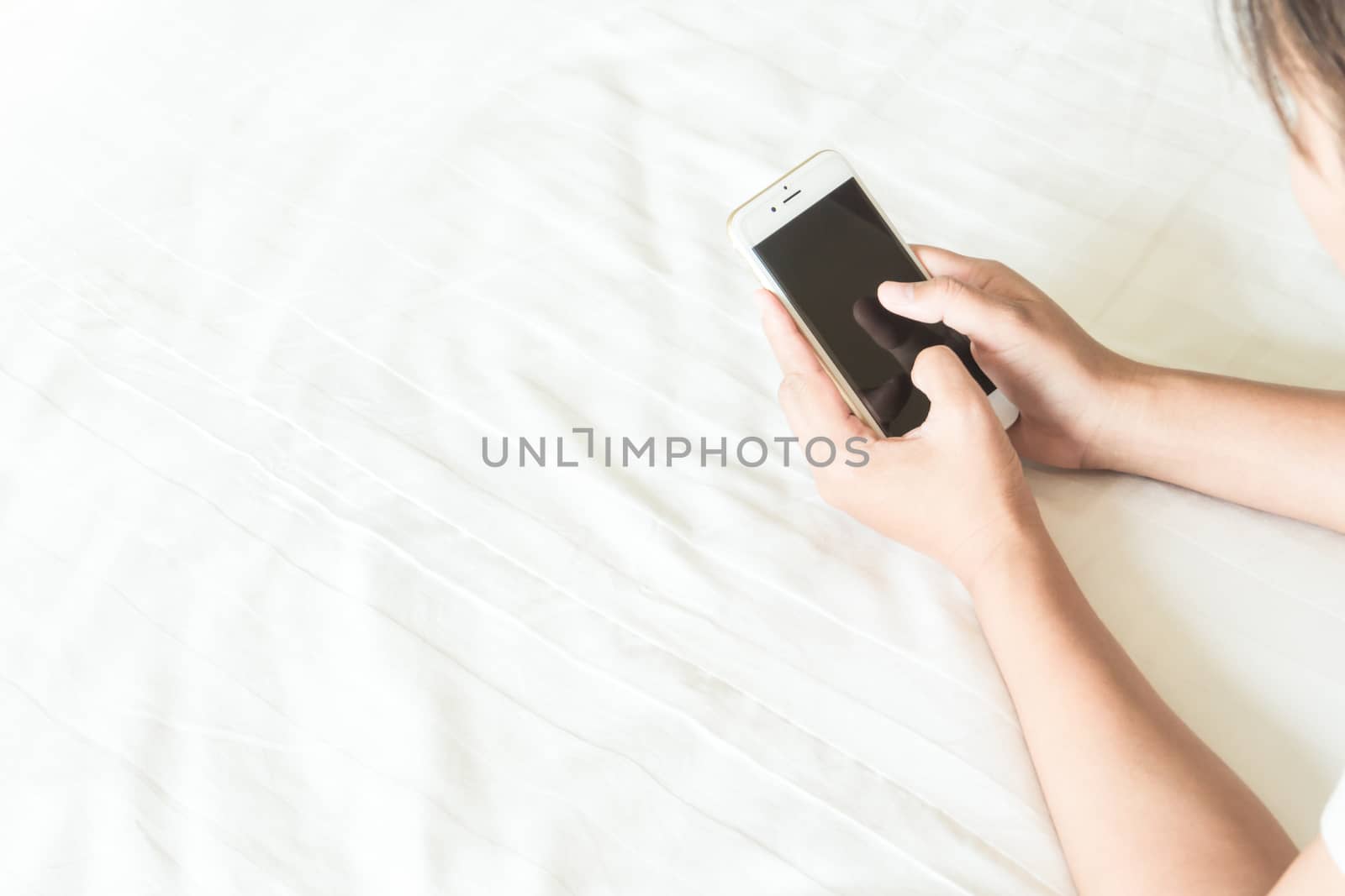 Closeup young woman holding smart phone lying on bed, happy and relax time concept