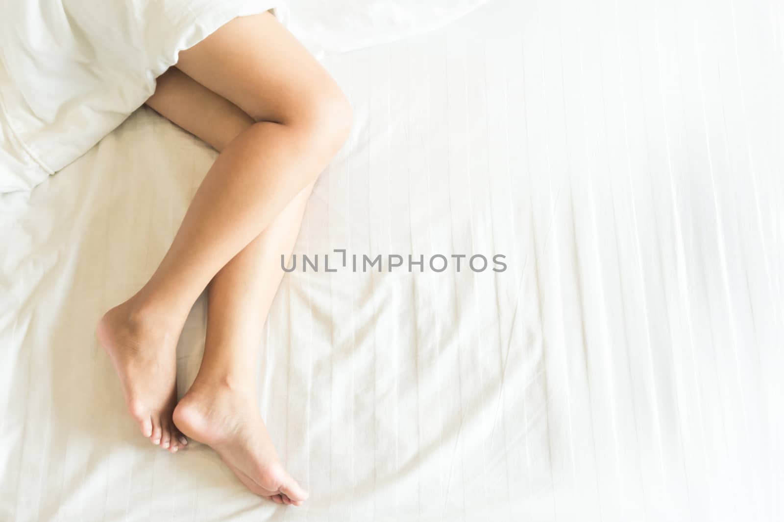 Closeup woman legs with sleeping on white bed, beauty and skin care concept, selective focus