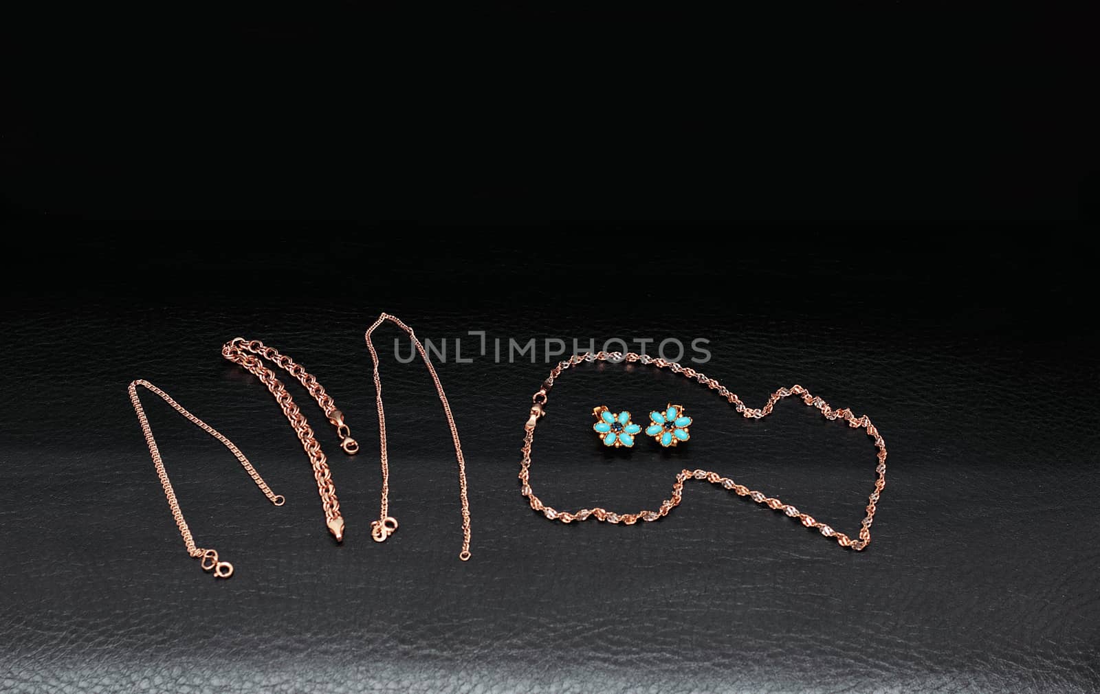 Womens gold jewelry chain, bracelets, earrings isolated black background.