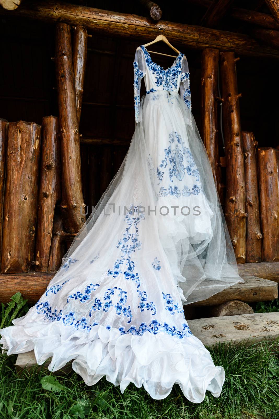 bridesmaid dress in the style of Gzhel hanging on a wooden beam in the input aperture of the house