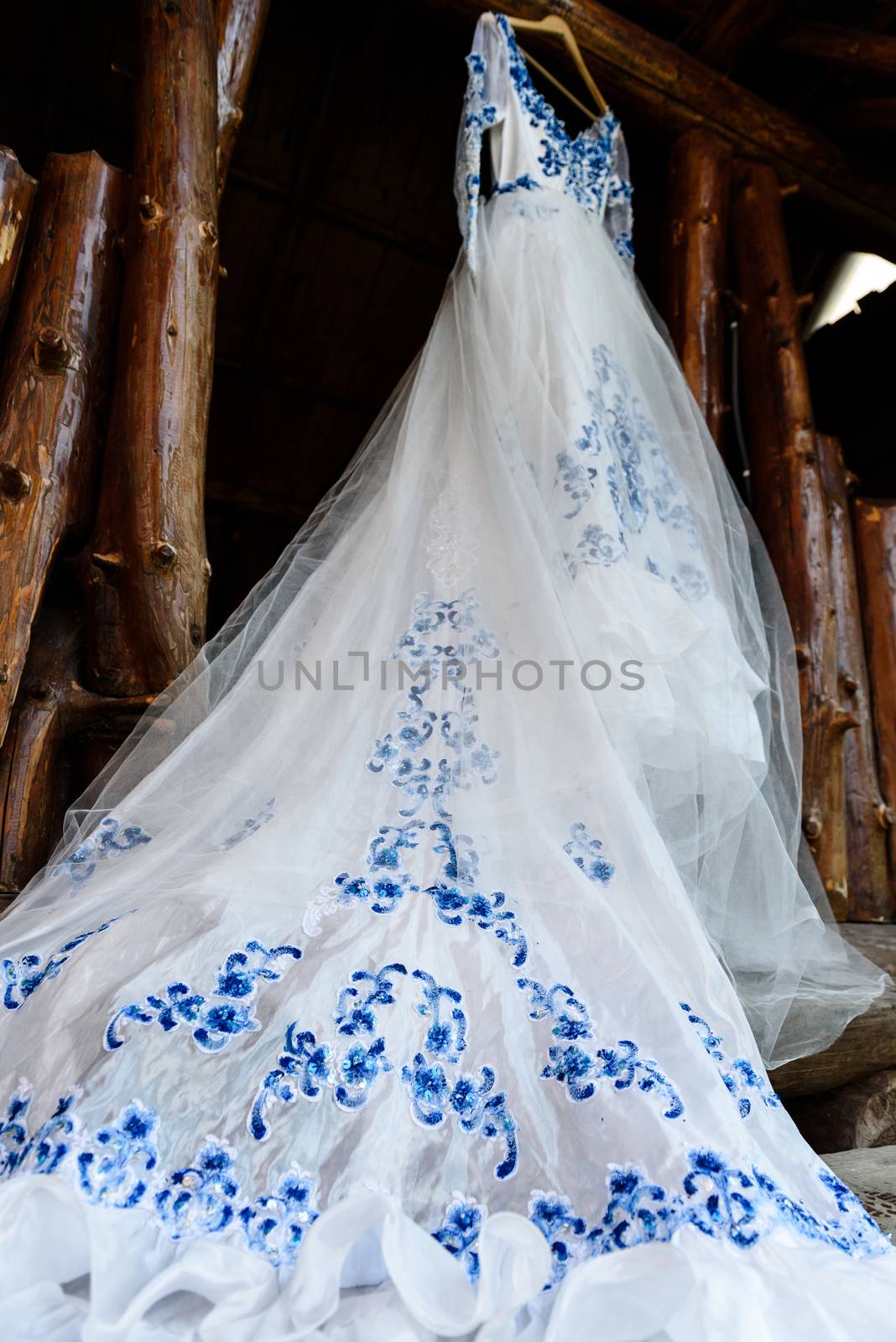 bridesmaid dress in the style of Gzhel hanging on a wooden beam in the input aperture of the house