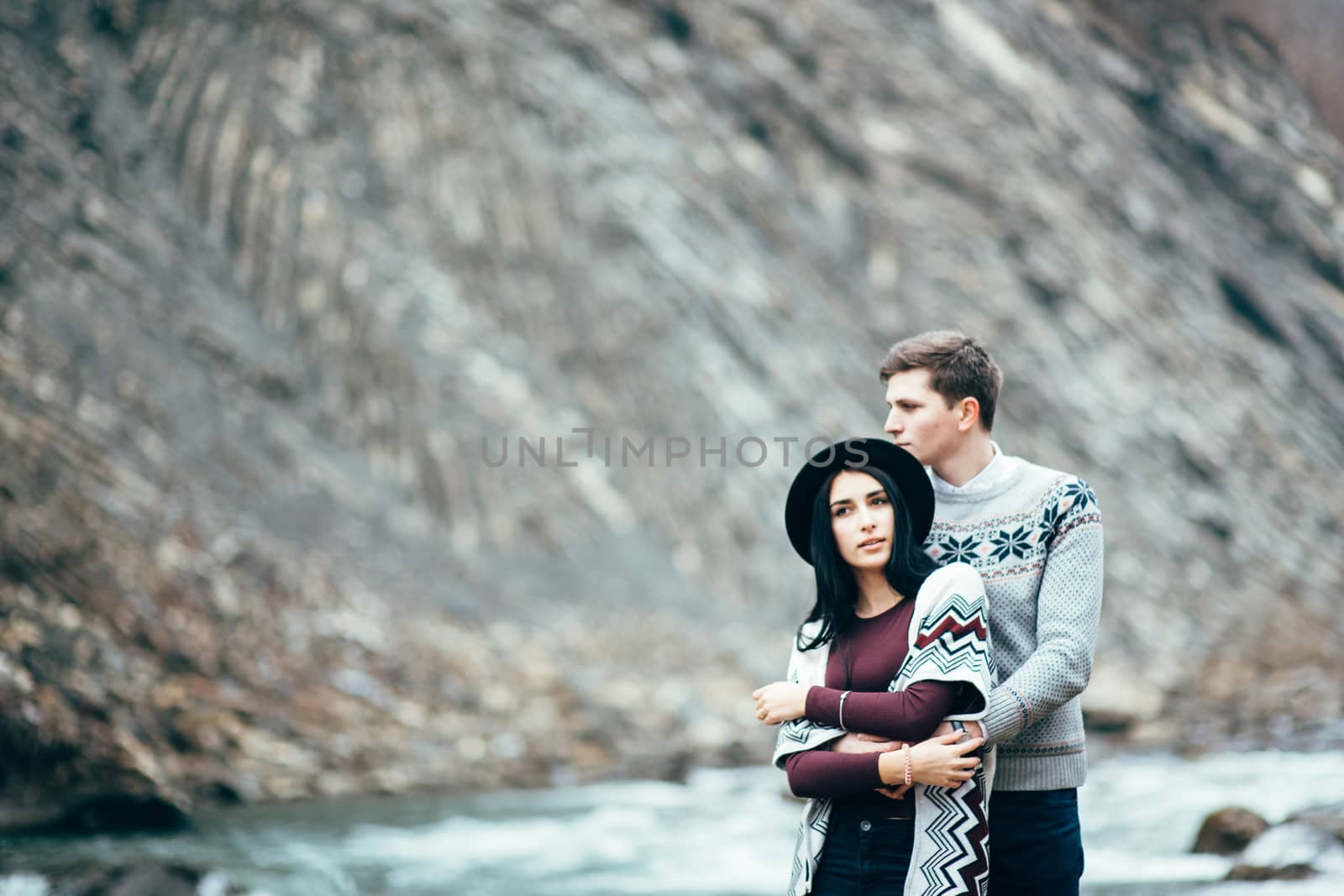 guy and girl in warm sweaters walking along a mountain river, love story