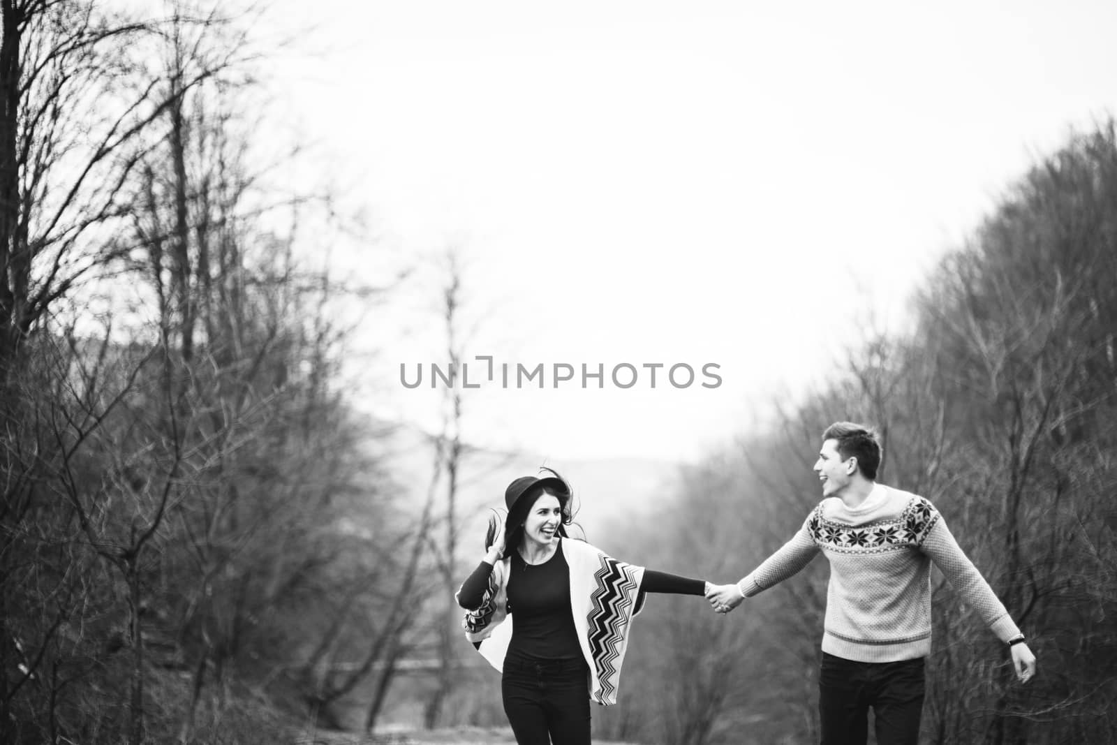 guy and girl in warm sweaters walking along a mountain river, love story