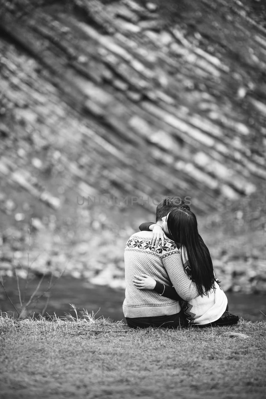 guy and girl in warm sweaters walking along a mountain river, love story