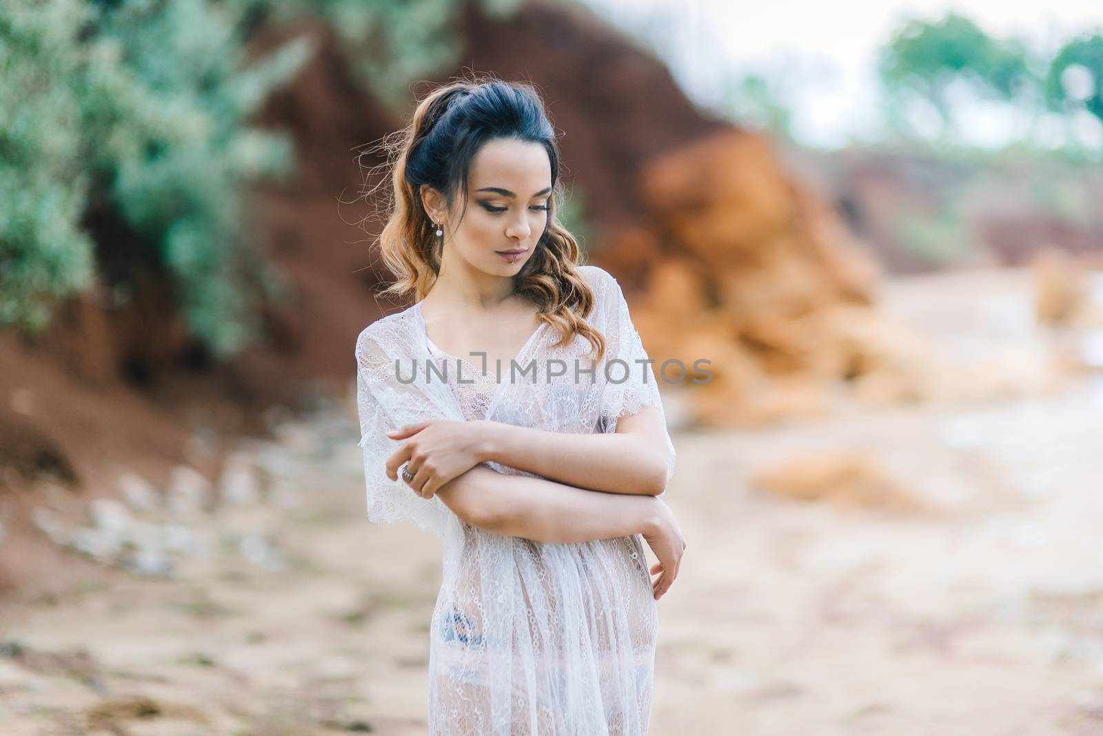 bride in her underwear and a dressing gown with a veil walks on the beach